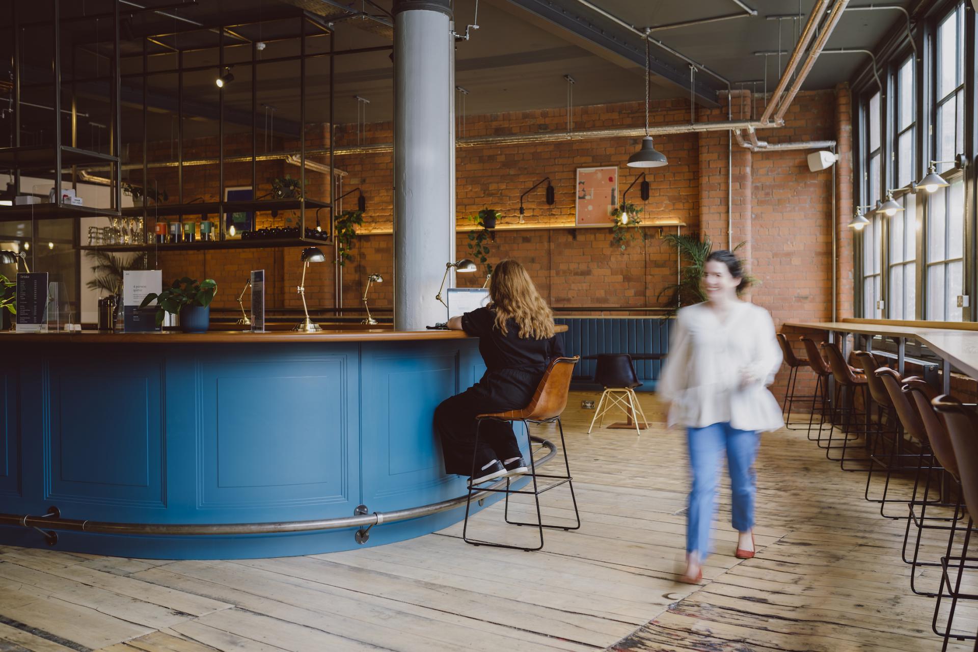 Stylish interior of a creative workspace with individuals working and walking in a vibrant, collaborative environment.