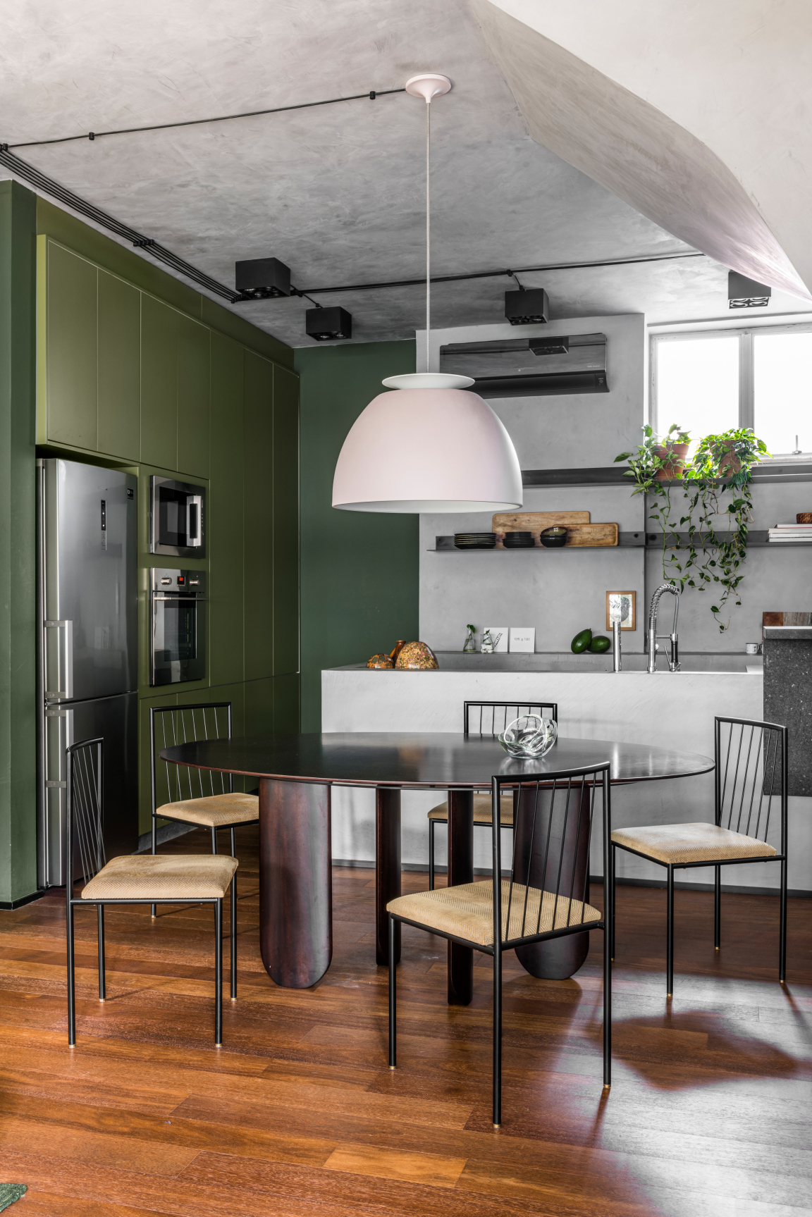 Contemporary dining area featuring a dark wood table, stylish chairs, and green cabinetry, embodying a harmonious connection with nature.