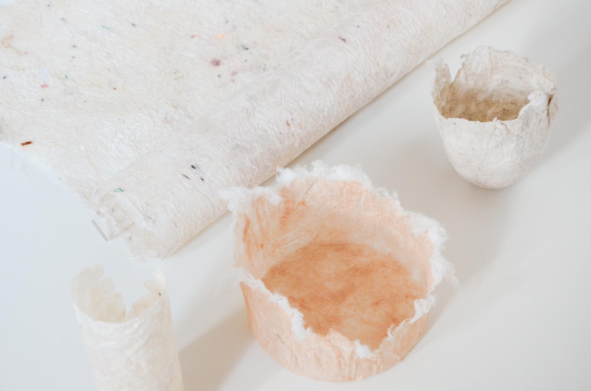 Biomaterial creations by Studio Sarmite, showcasing unique containers and textured paper made from reimagined waste.