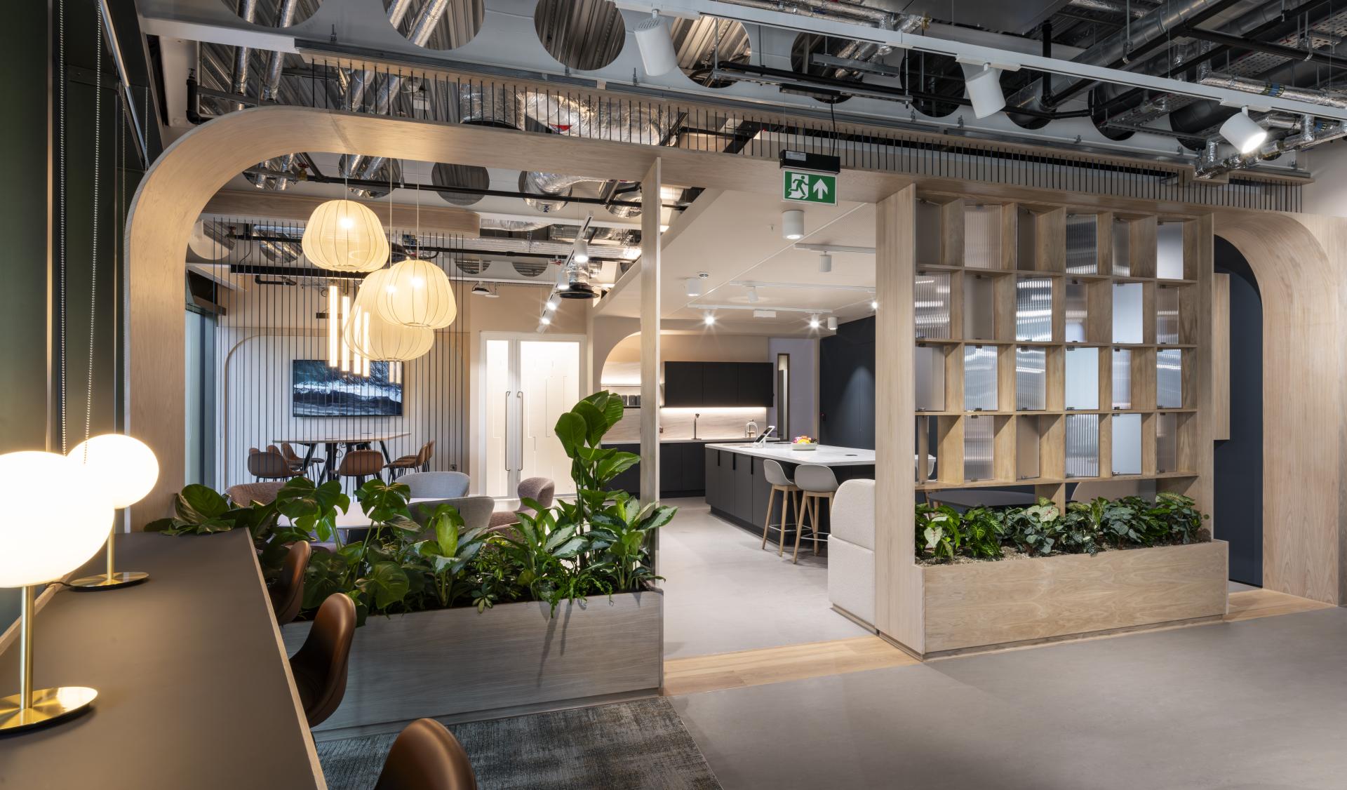 Modern interior design featuring open spaces, greenery, stylish lighting, and a kitchen area, reflecting innovative design principles.