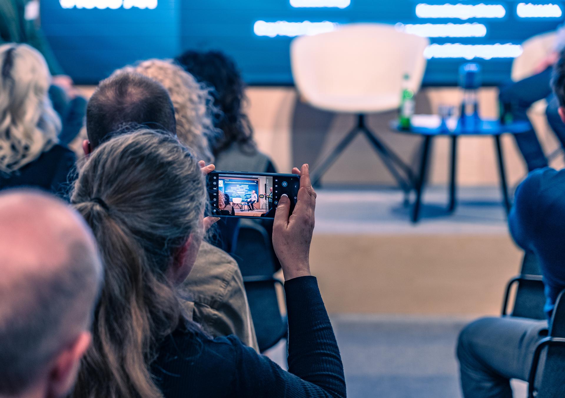 Audience member filming a panel discussion on net zero carbon buildings at Material Source Studio Glasgow.