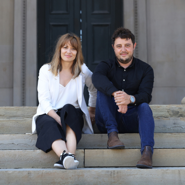 Kasia Borkowska and a colleague seated on steps, discussing harmonious architecture and interiors in Liverpool's real estate context.