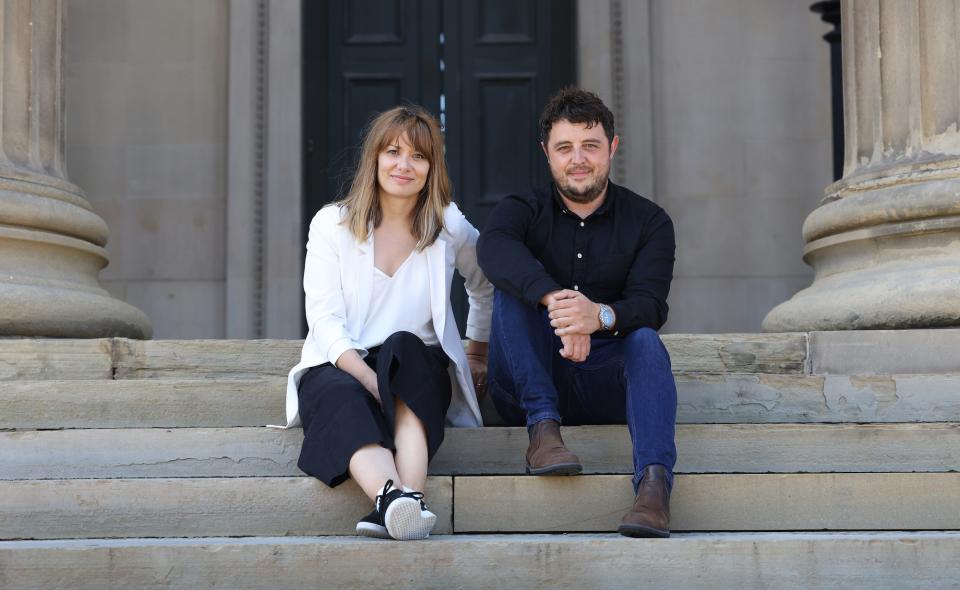 Kasia Borkowska and a colleague seated on steps, discussing harmonious architecture and interiors in Liverpool's real estate context.