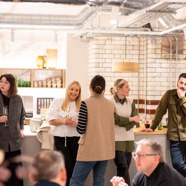 Networking event with diverse professionals discussing EDI culture in a modern, inviting space.