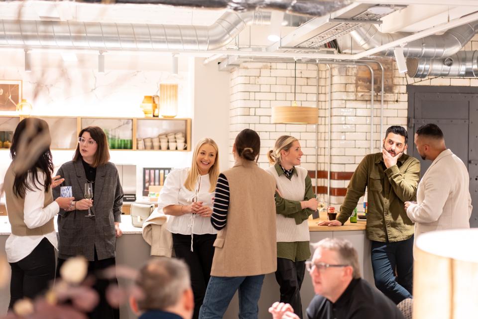 Networking event with diverse professionals discussing EDI culture in a modern, inviting space.