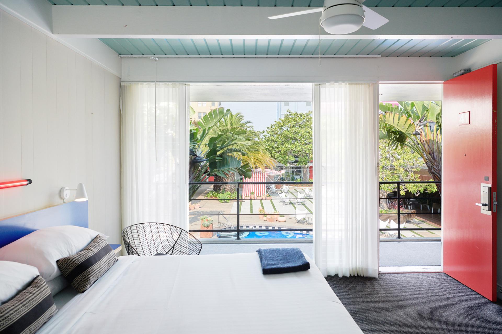 Bright hotel room at Phoenix Hotel, featuring modern design, large windows with garden view, and open door.
