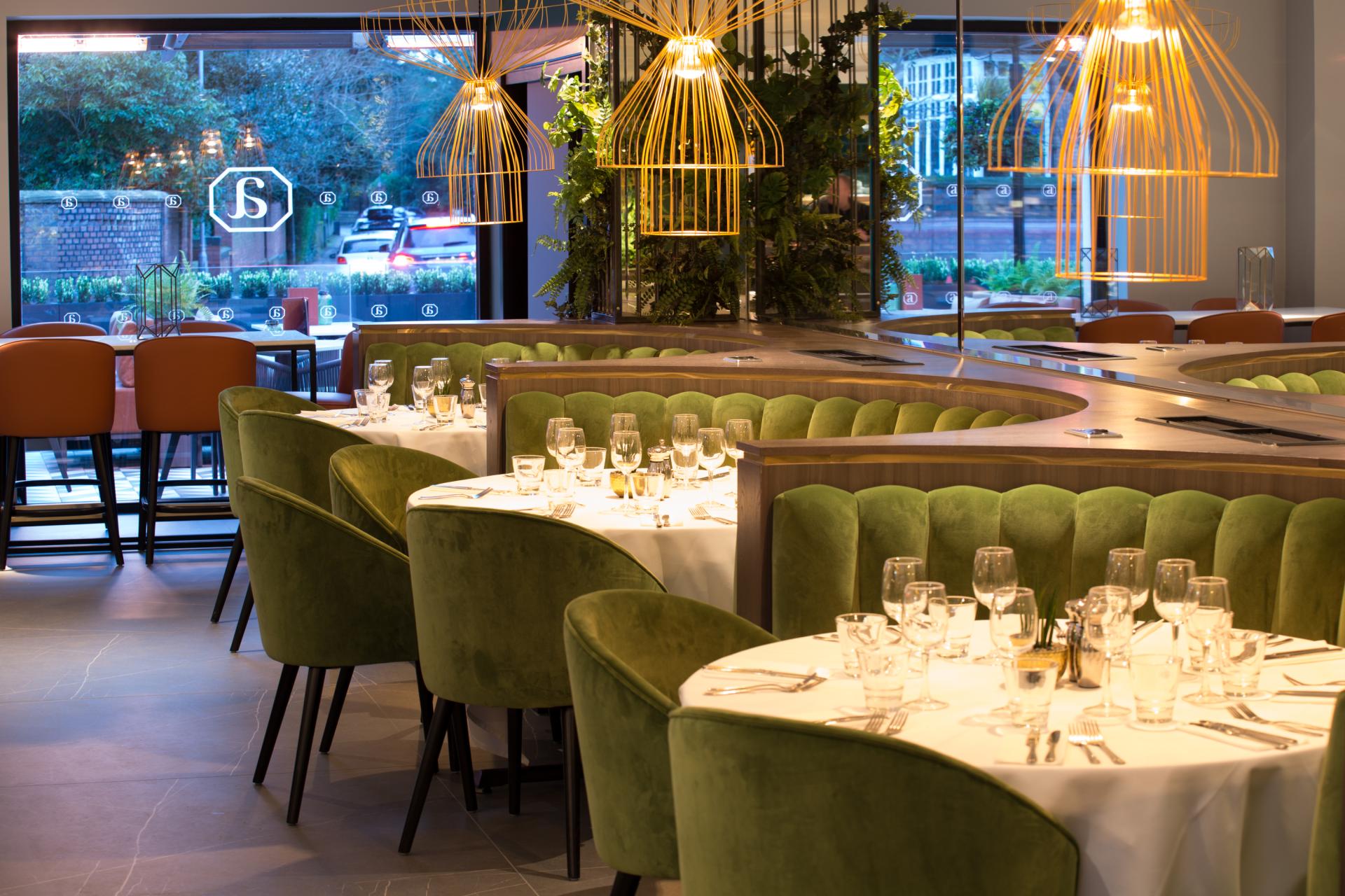 Stylish dining area at Albert’s Didsbury featuring green upholstered chairs and modern lighting, reflecting SpaceInvader's design.