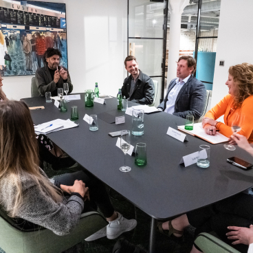 Group discussion on Manchester's property sector trends, featuring professionals seated at a conference table with drinks.