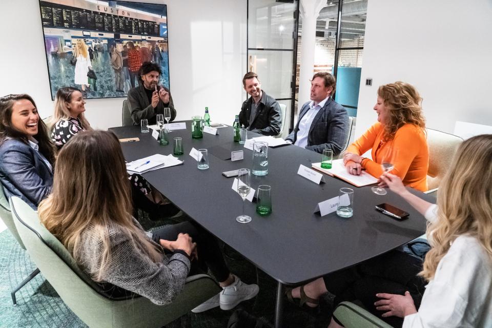 Group discussion on Manchester's property sector trends, featuring professionals seated at a conference table with drinks.