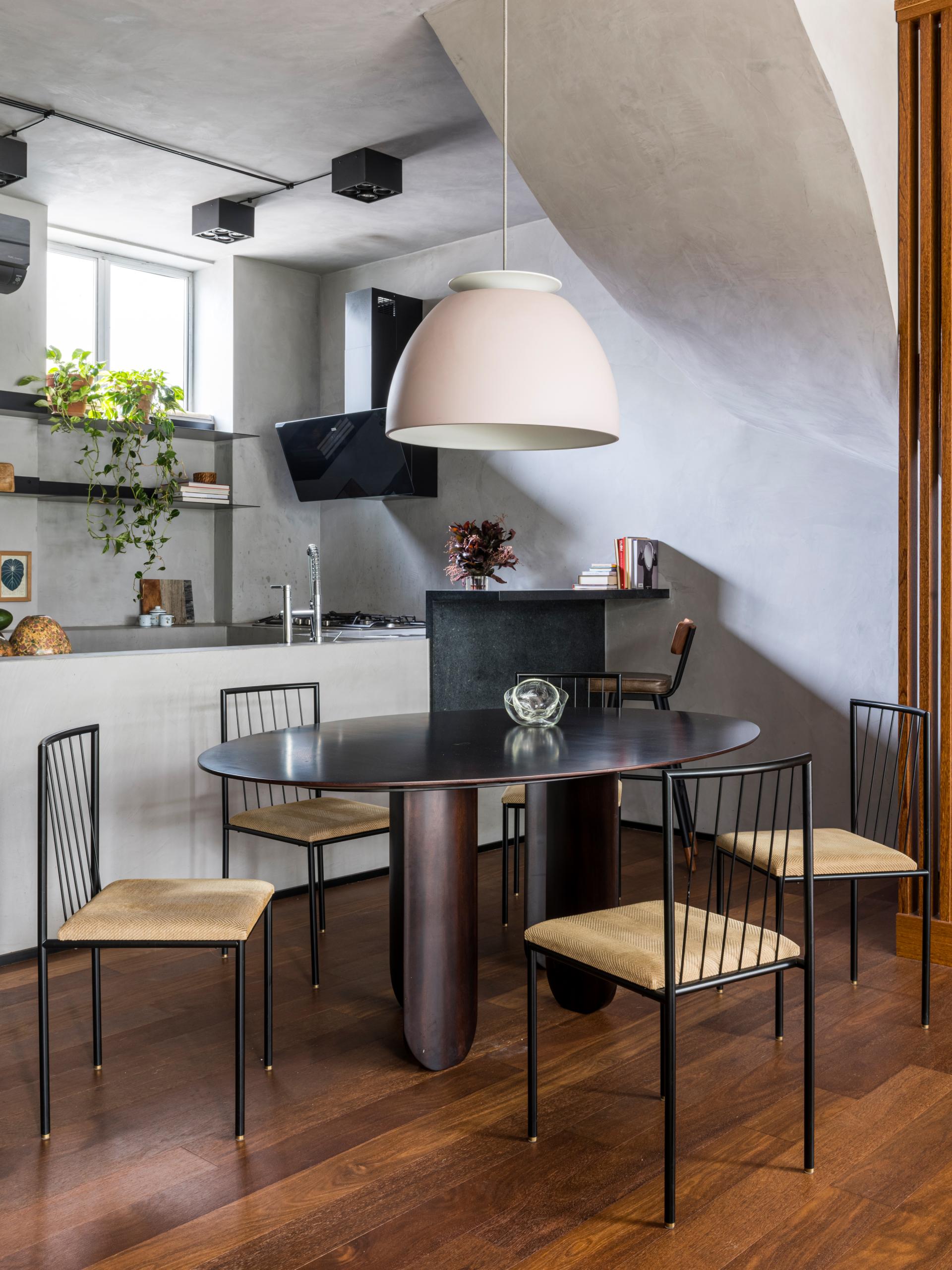 Elegant dining area featuring a round black table, stylish chairs, and a modern pendant light in a nature-inspired design.