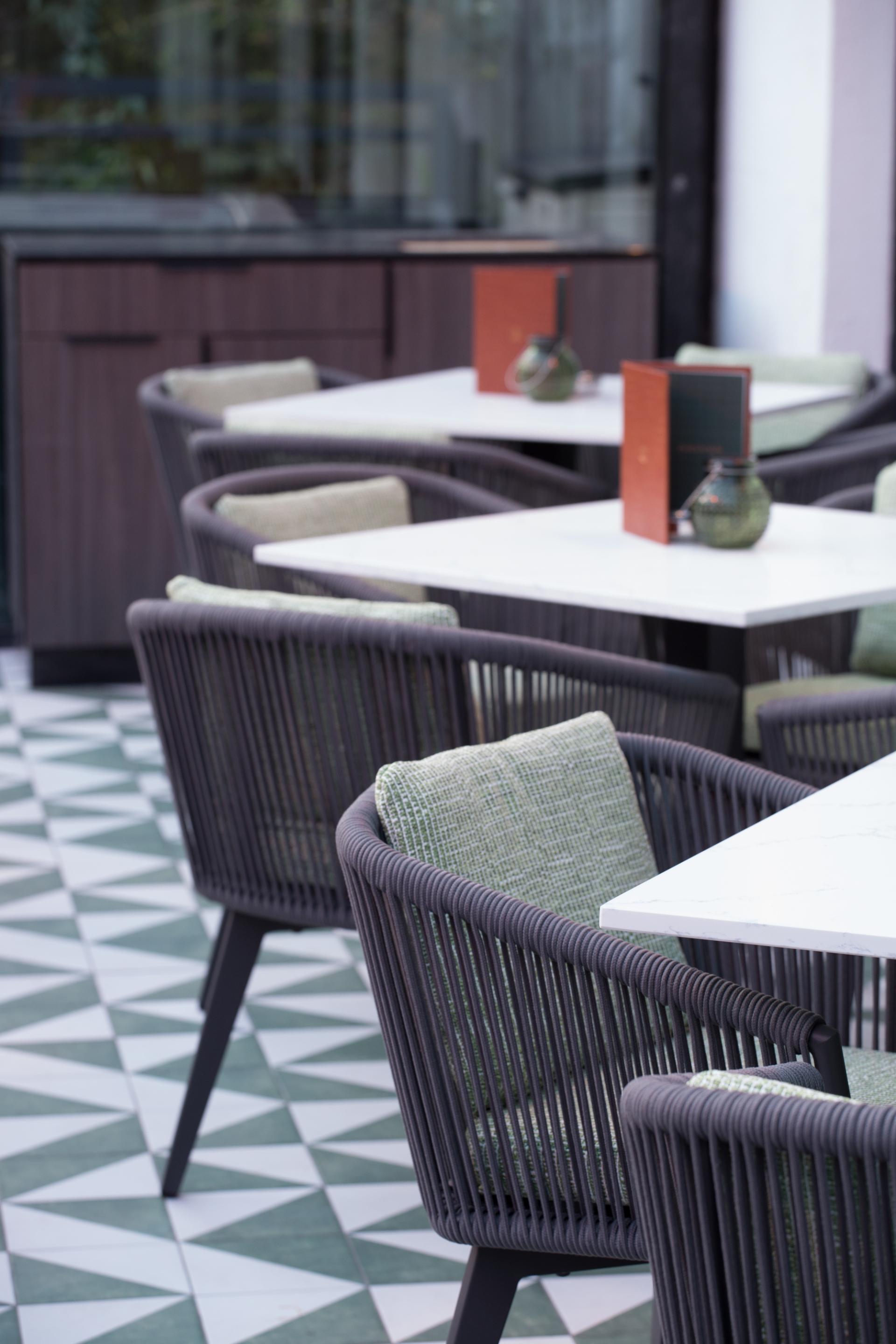 Stylish outdoor seating area at Albert's Didsbury featuring modern chairs and geometric tiled flooring.
