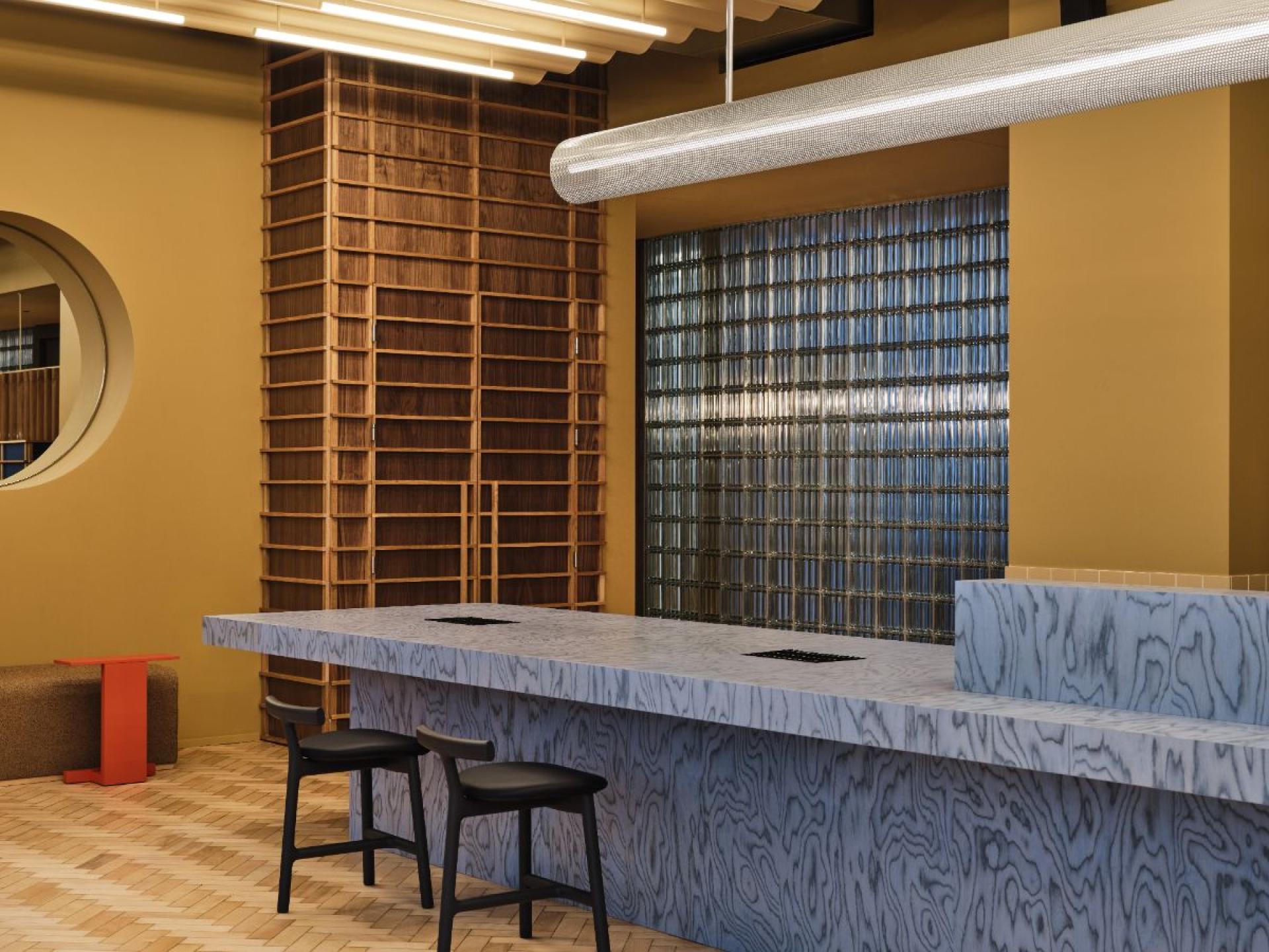 Stylish flexible workspace interior featuring a modern bar counter, wooden shelving, and vibrant color accents.