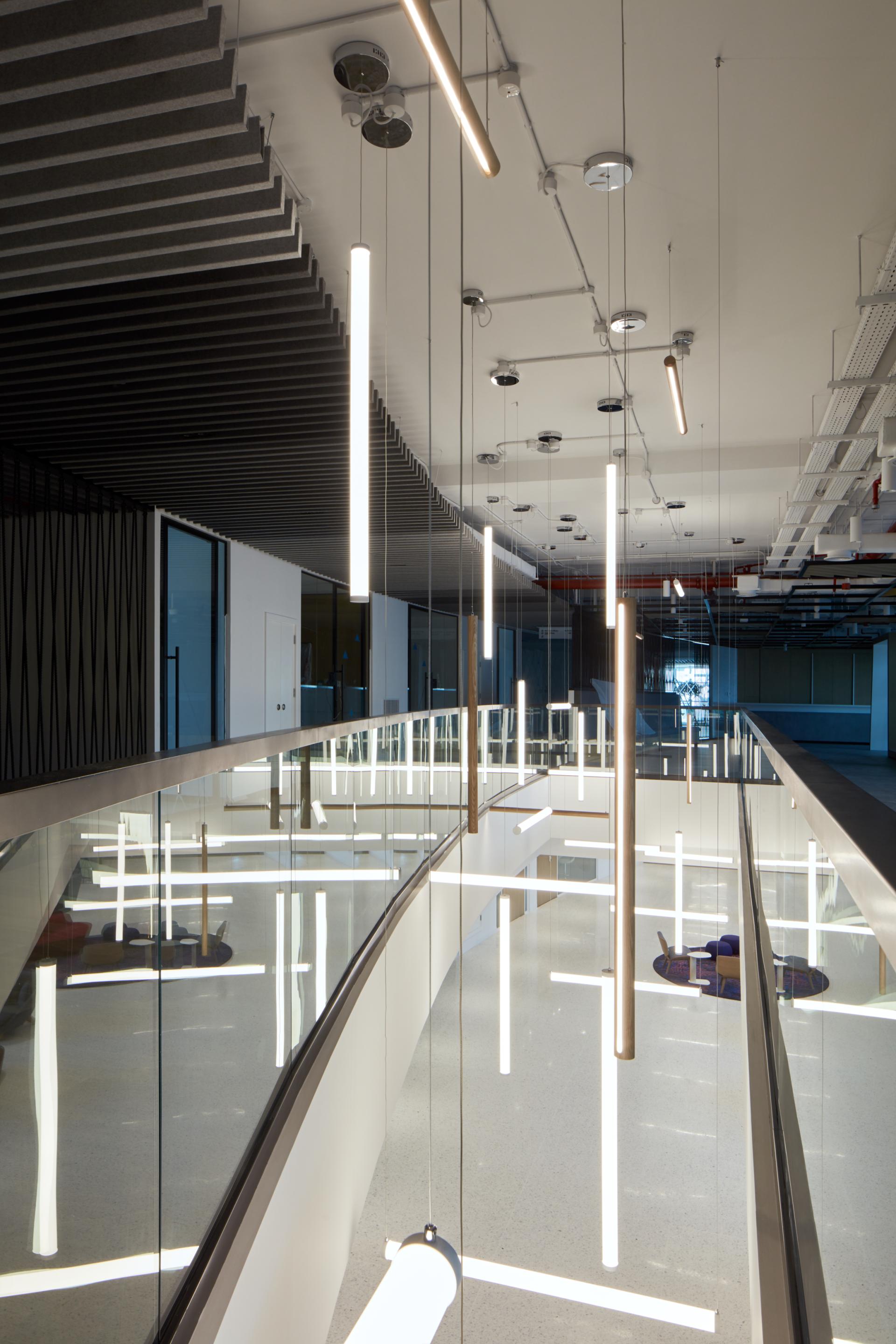 Modern interior design of American University of Sharjah's Research Technology and Innovation Park, featuring sleek lighting and glass railings.