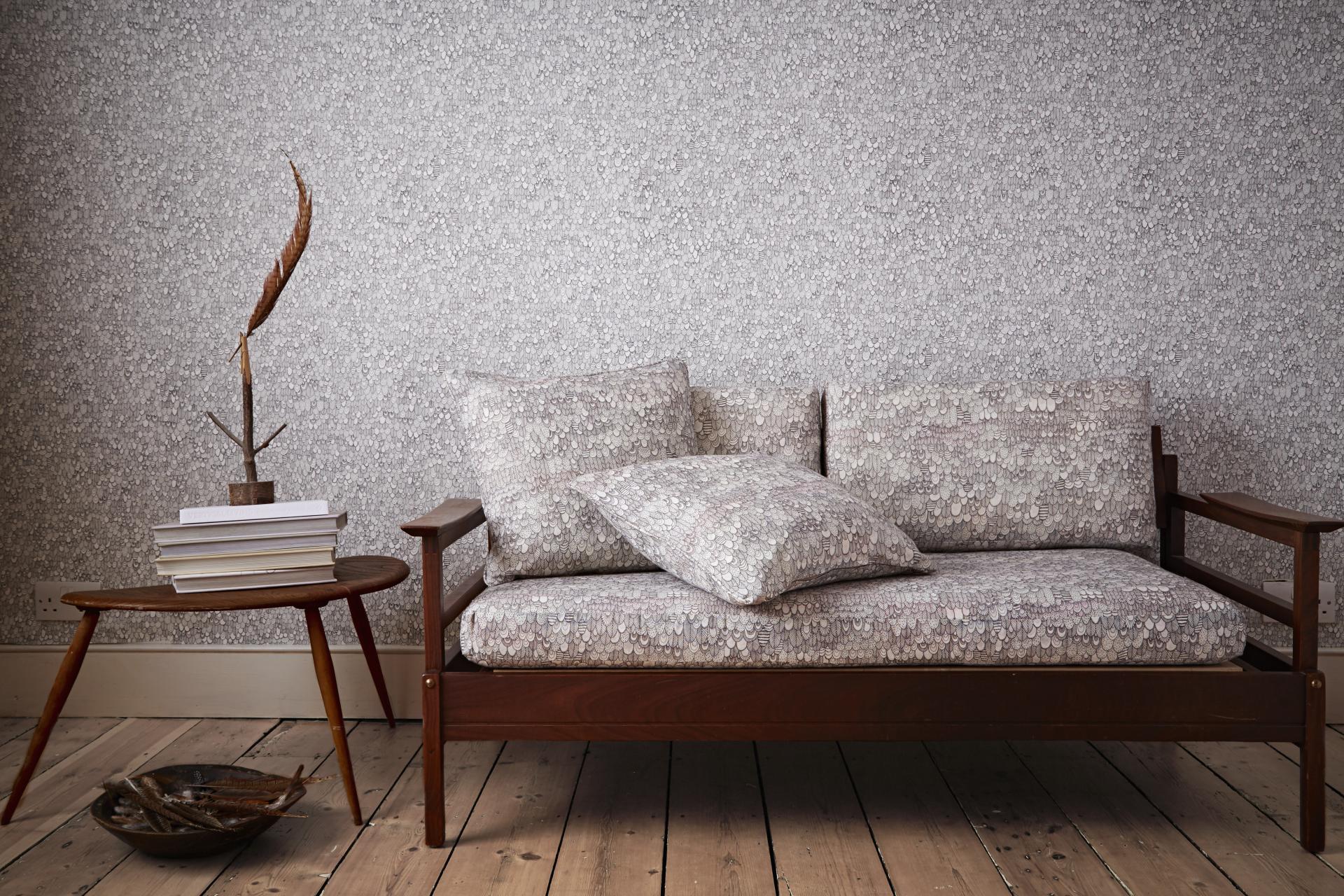 Elegant sofa adorned with nature-inspired patterned cushions, set against a textured wallpaper and wooden floor.