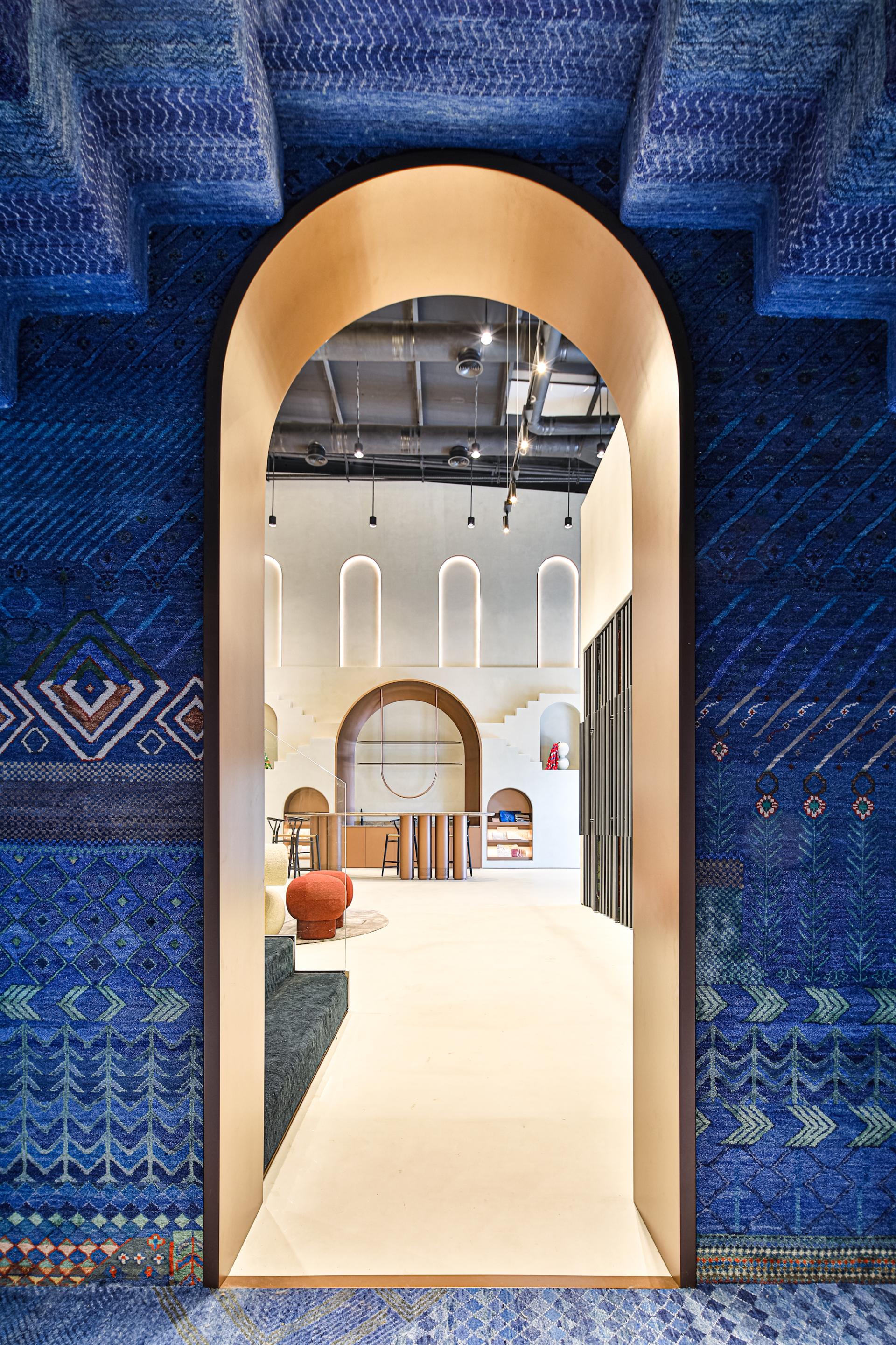 A vibrant, arch-framed view of the Jaipur Rugs Dubai showroom showcasing Rajasthani-inspired design elements and decorative carpets.