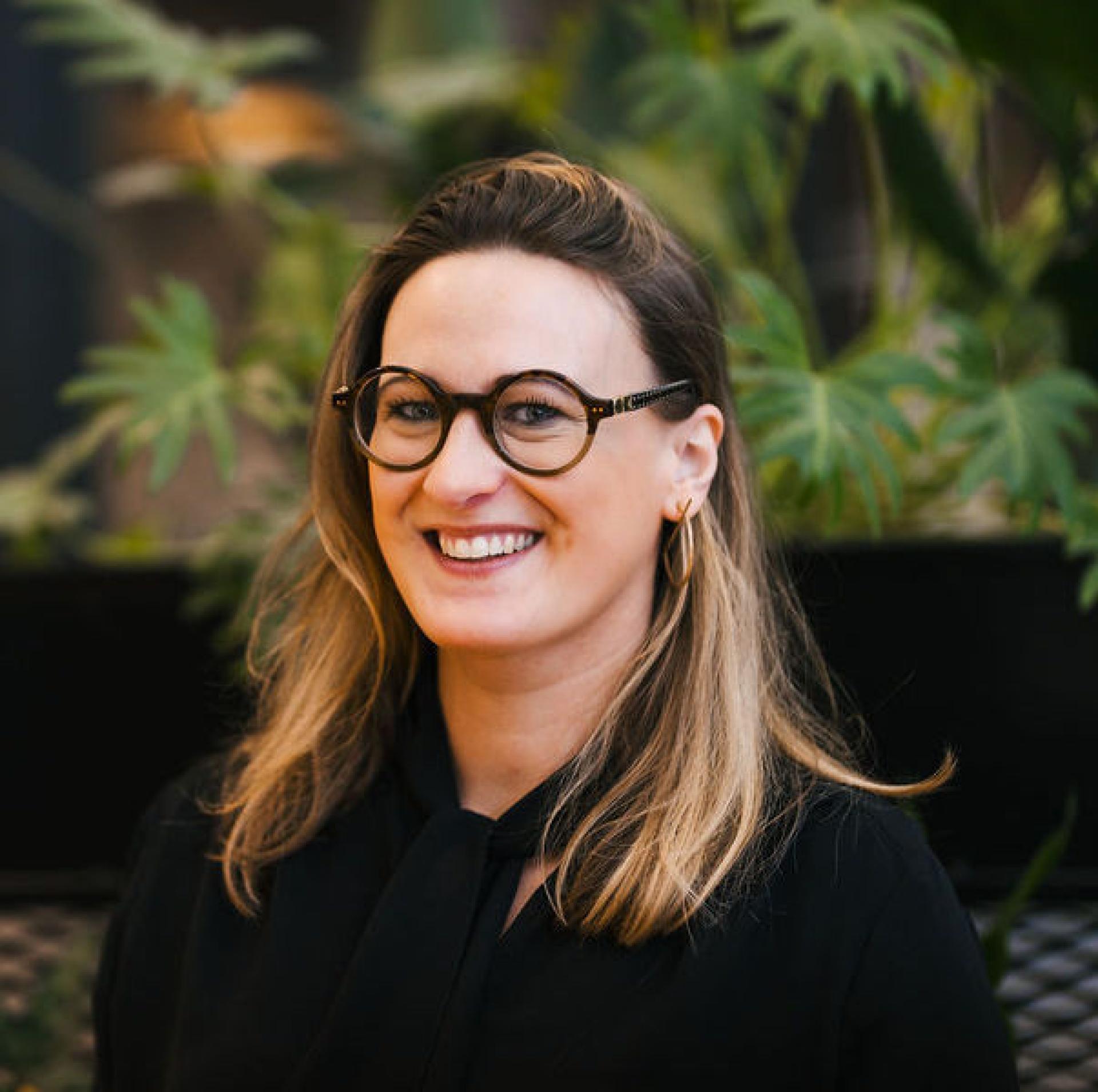 Professional woman smiling amidst greenery, representing insights on Glasgow's property outlook and future trends.