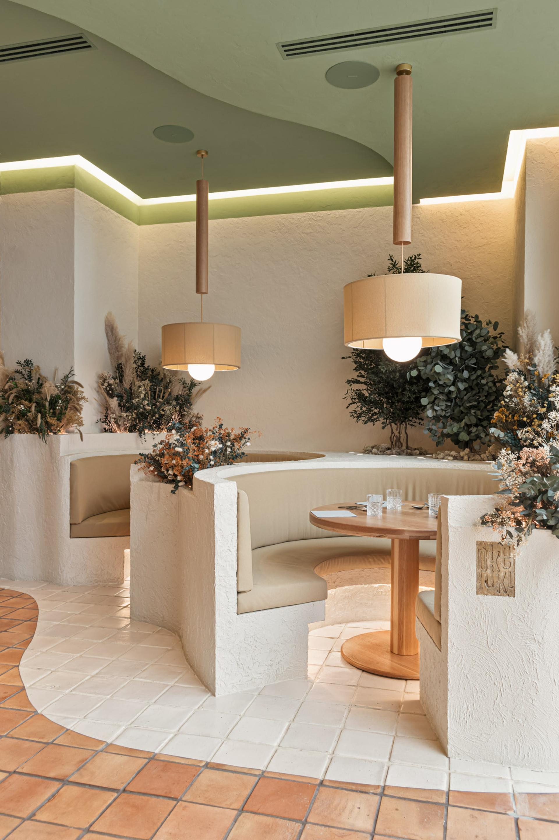Elegant dining area featuring natural decor with plants, soft lighting, and cozy circular seating at Huesca restaurant.