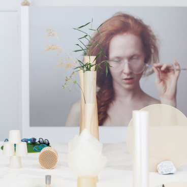 Nuatan bioplastic products displayed on a table, with a close-up of plants and a model in the background.