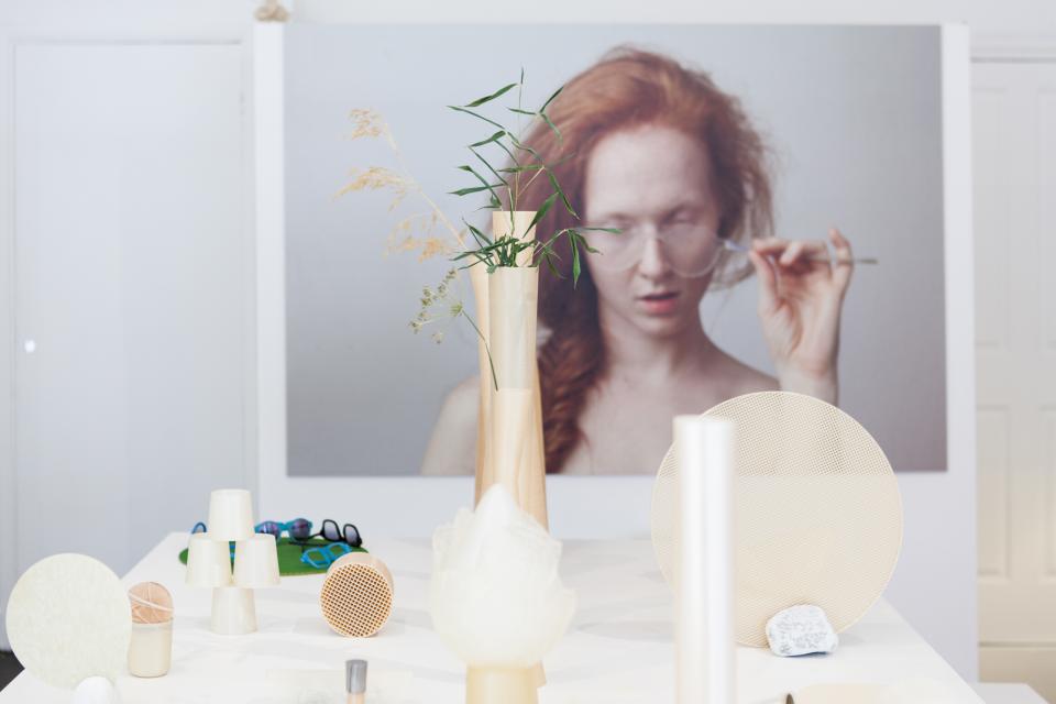 Nuatan bioplastic products displayed on a table, with a close-up of plants and a model in the background.