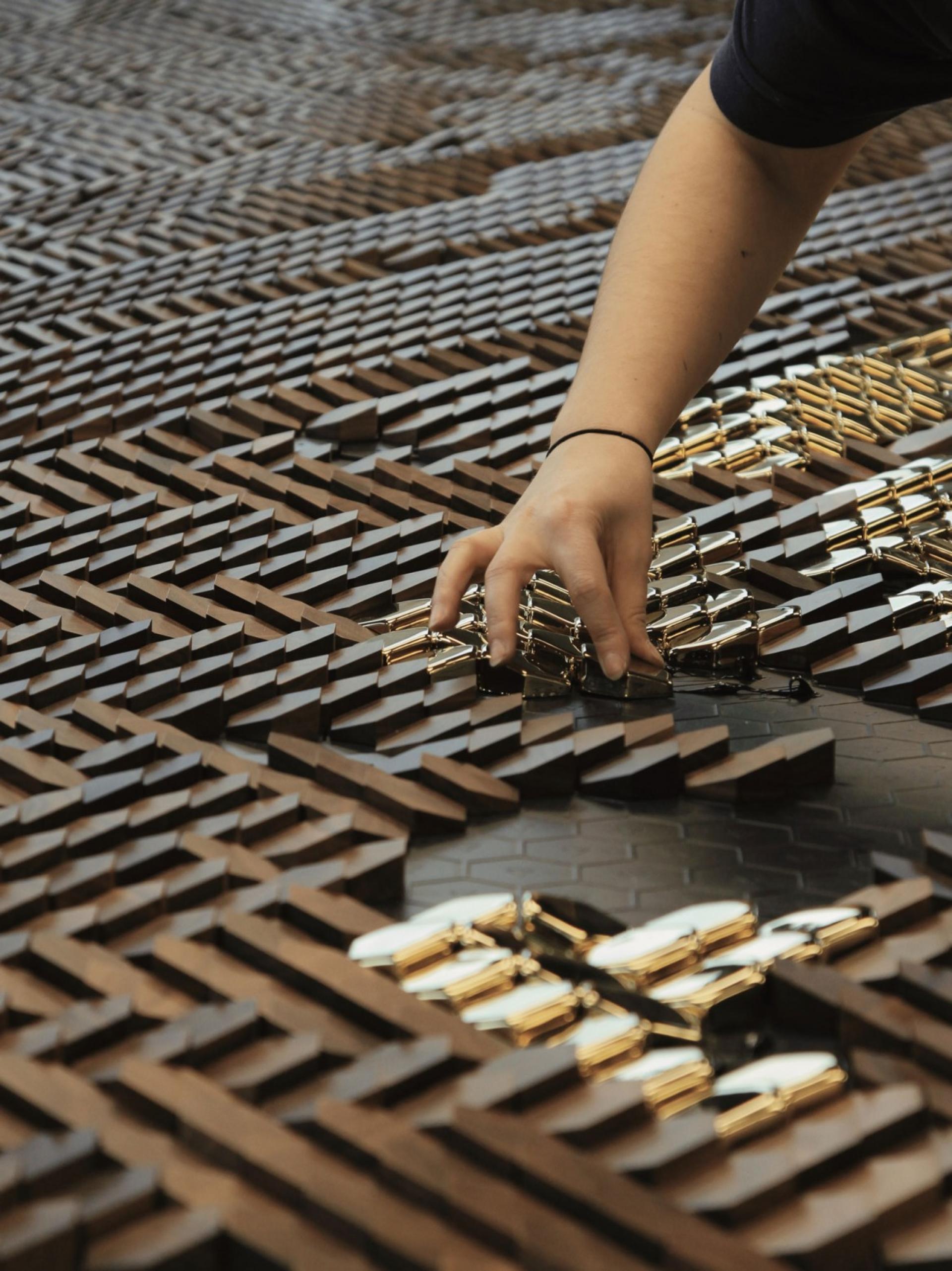 A close-up of a hand arranging textured materials, showcasing innovative design and experimentation at Giles Miller Studio.