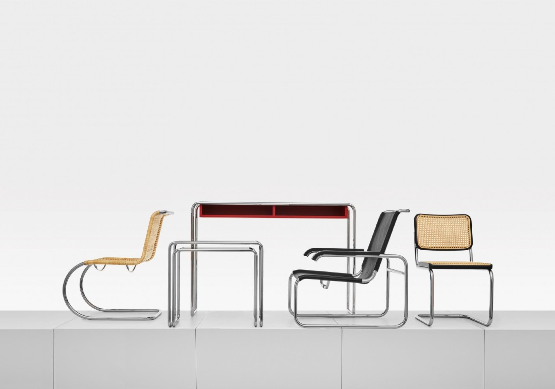 Modern minimalist furniture display featuring four distinctive chairs and a sleek desk for stylish office decor.