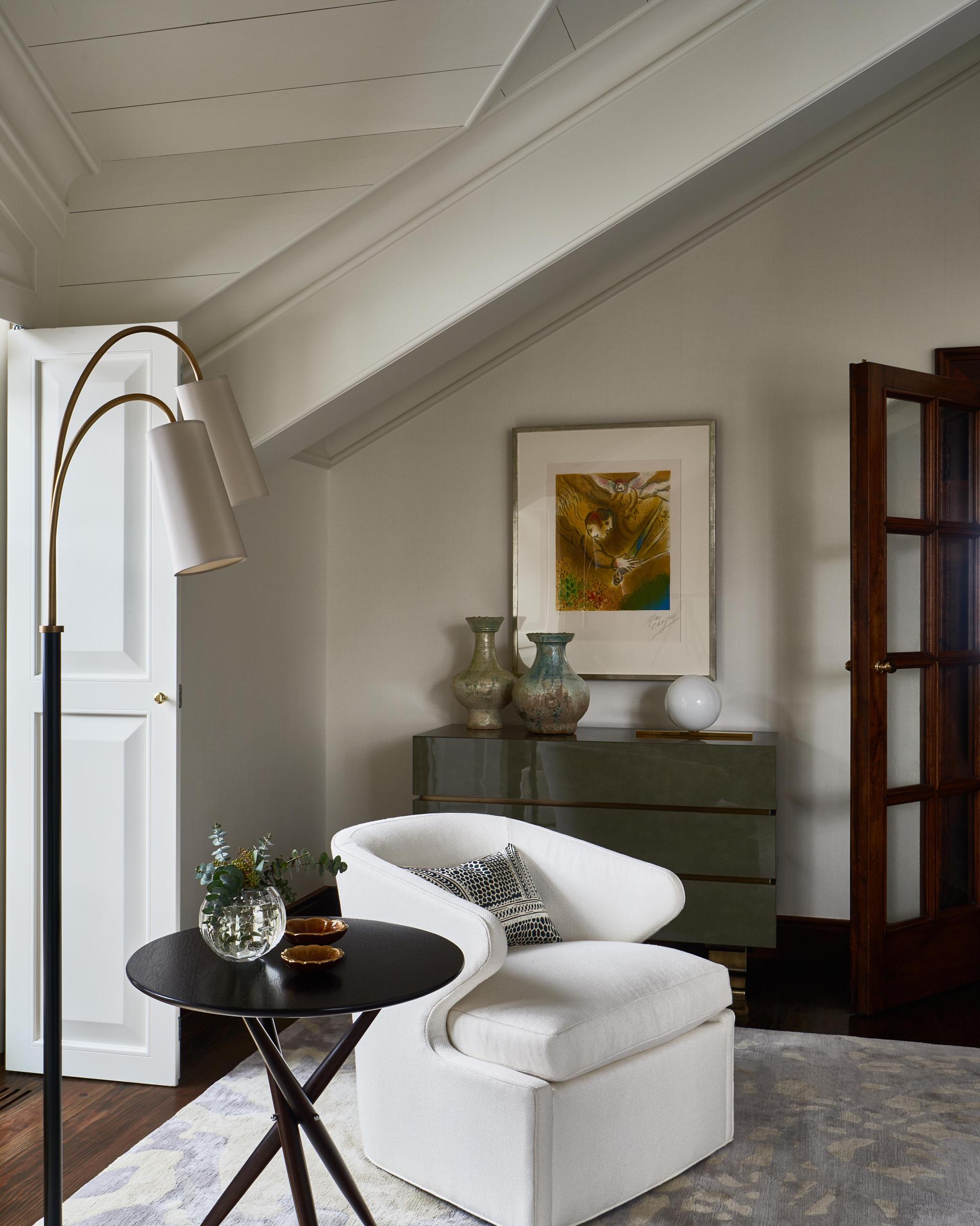 Stylish chalet interior featuring a white armchair, decorative lamp, and elegant furnishings designed by Champalimaud Design.