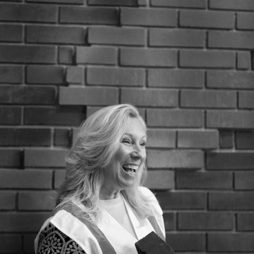 Lucy Black, head of business development at K-BRIQ, holding an eco-friendly brick against a textured wall.