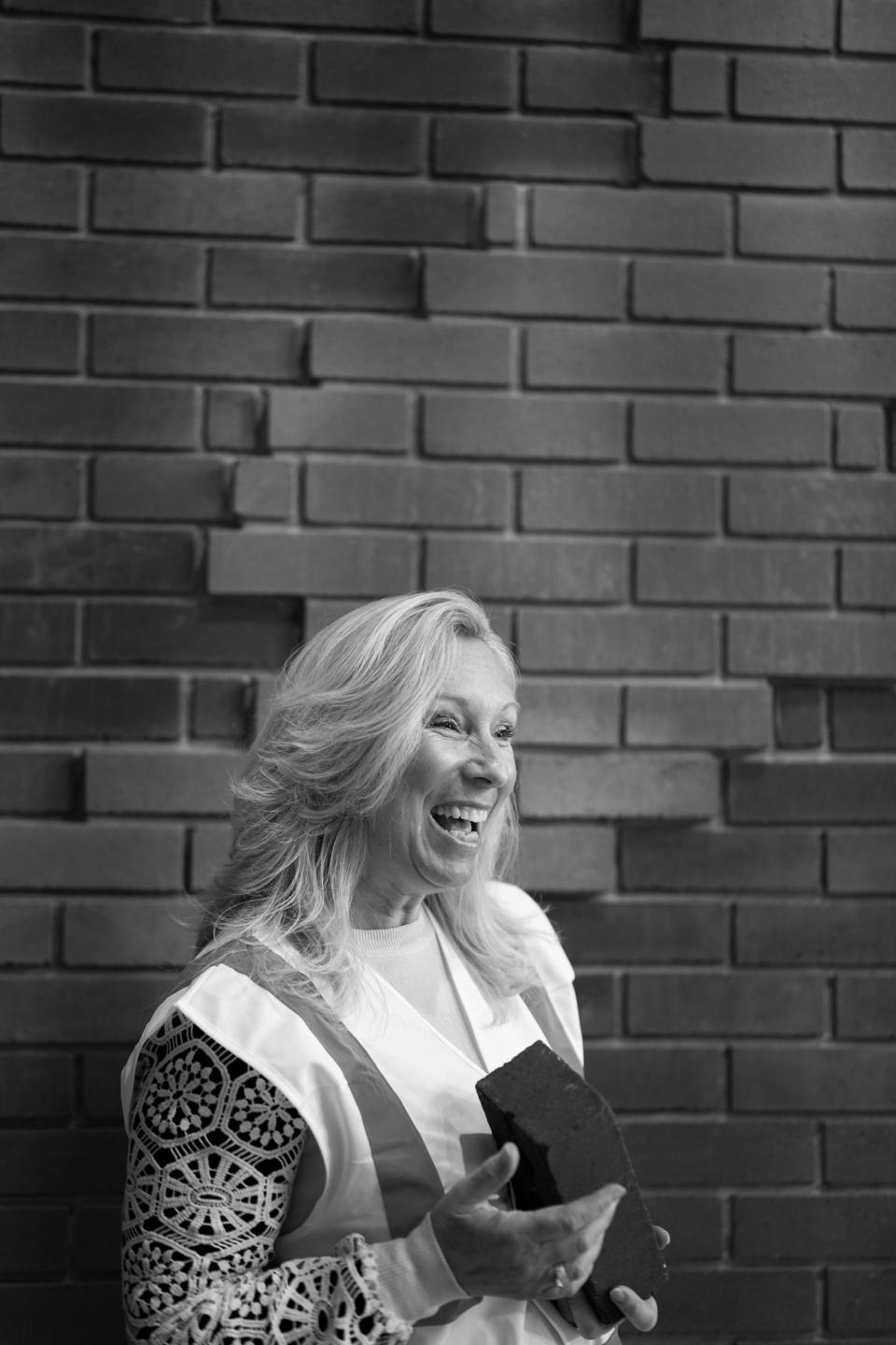 Lucy Black, head of business development at K-BRIQ, holding an eco-friendly brick against a textured wall.