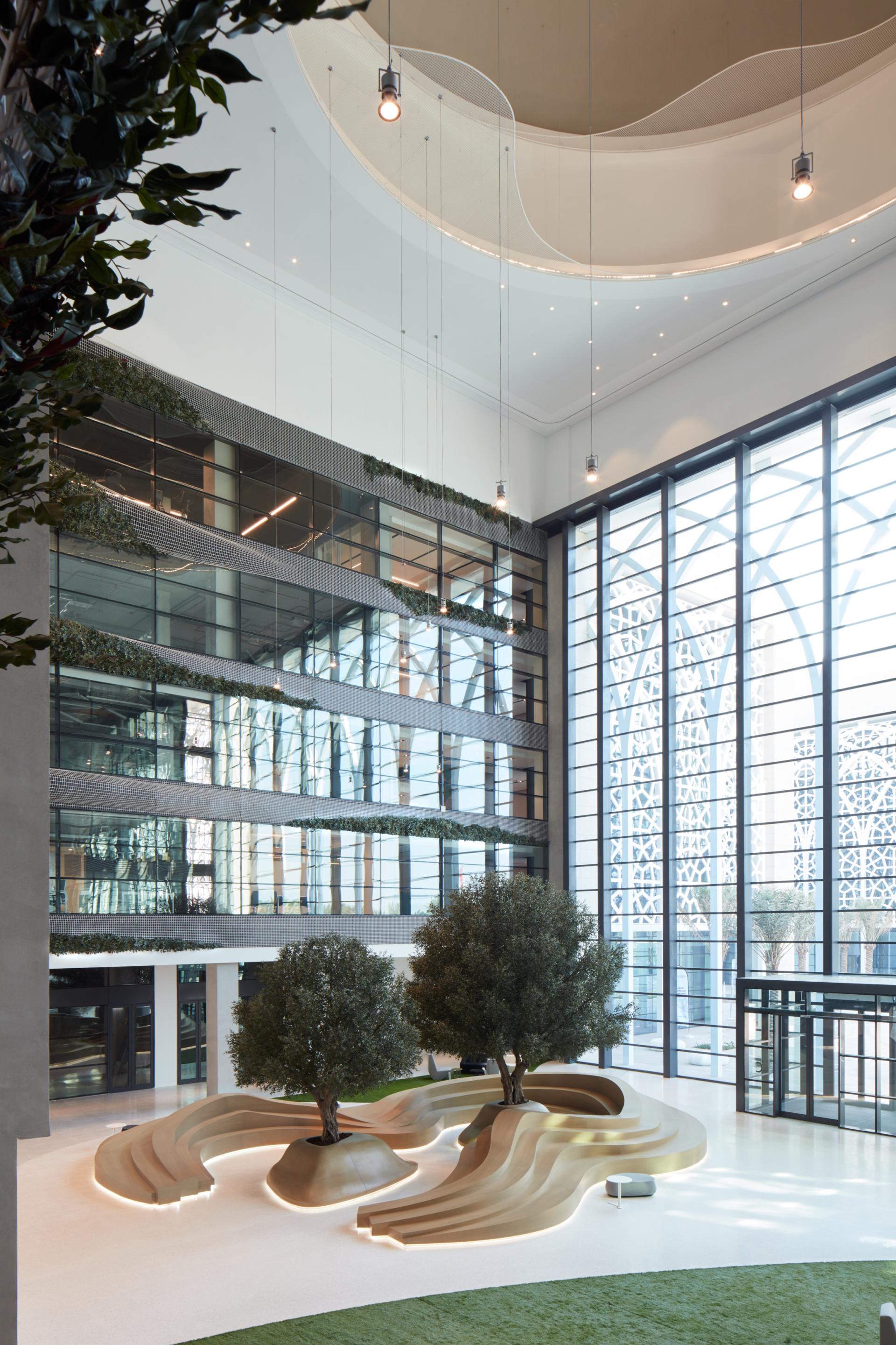 Modern atrium of American University of Sharjah's Research Technology Park, featuring natural elements and contemporary design by ROAR Studio.