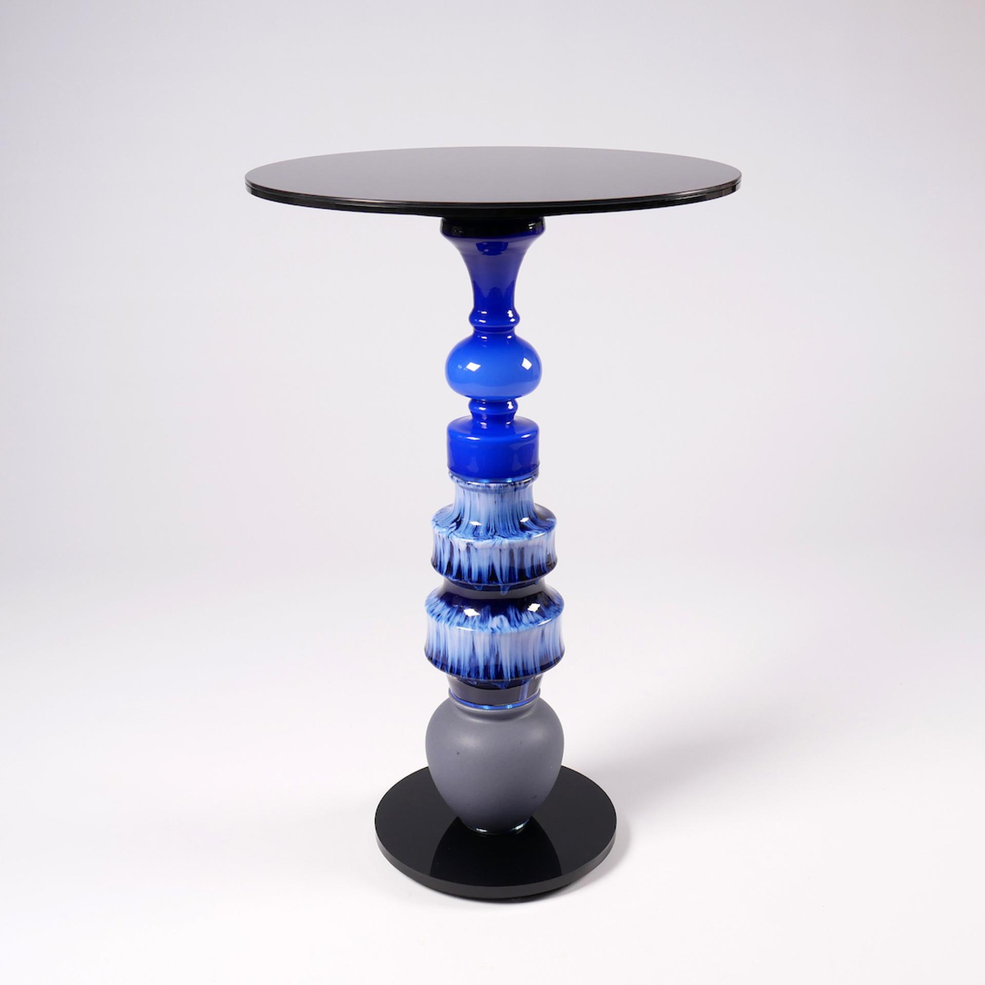 Contemporary glass and metal side table featuring a vibrant blue base, showcasing innovative German design.