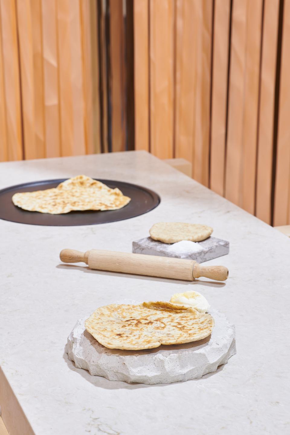 Freshly baked flatbreads displayed on textured Caesarstone surfaces, showcasing the harmony of food and design.