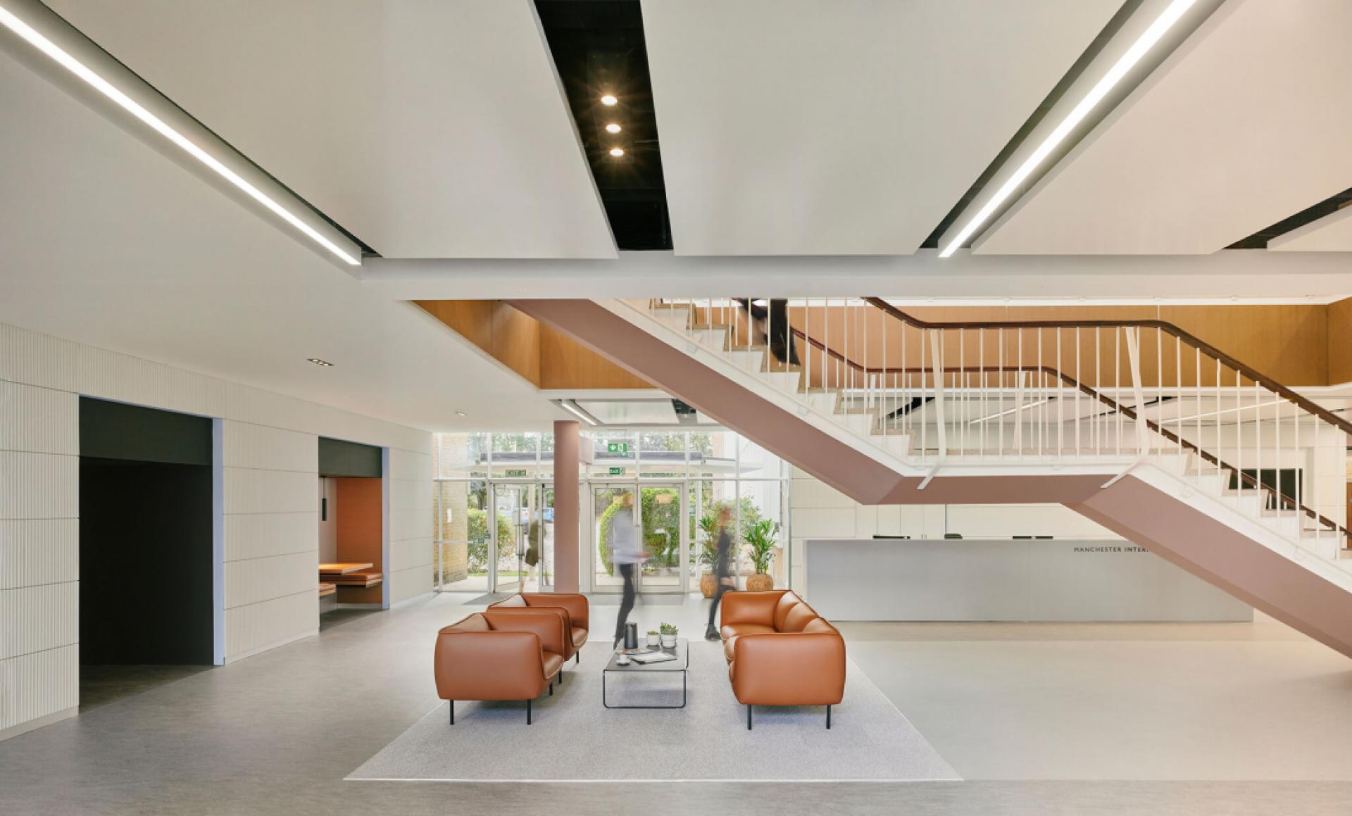 Modern lobby interior featuring comfortable seating, a staircase, and large windows for natural light in a hospitality setting.