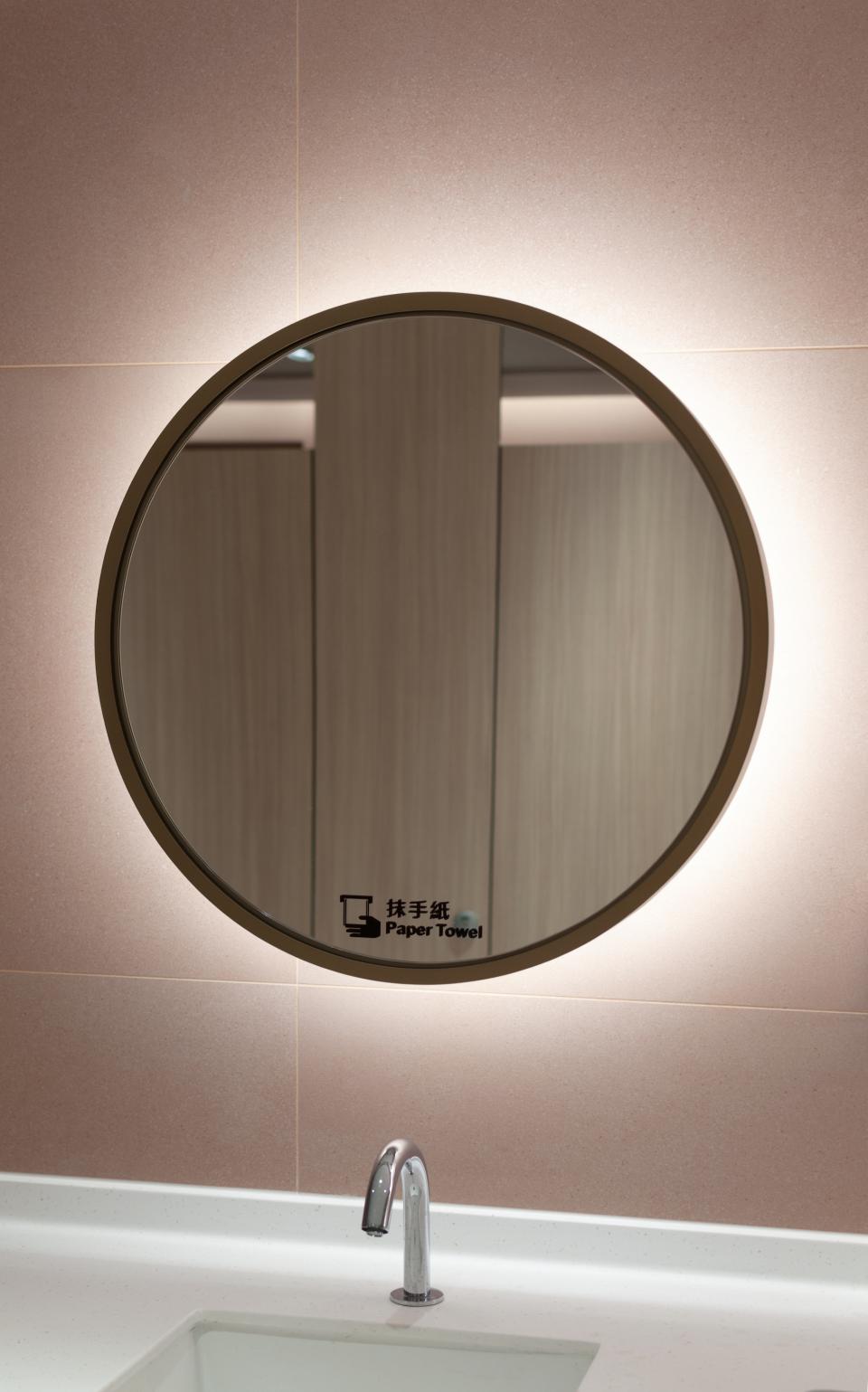 Round illuminated mirror above a sink in a modern restroom, showcasing a stylish design typical of Unicorn Stores' aesthetic.