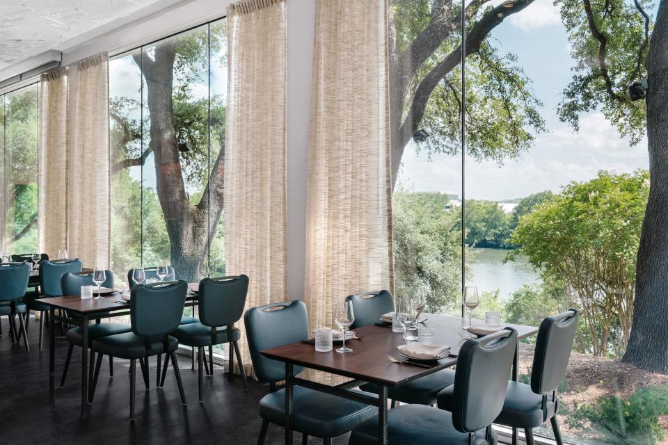 Modern restaurant interior featuring pale pink and natural surfaces, with large windows showcasing a scenic outdoor view.