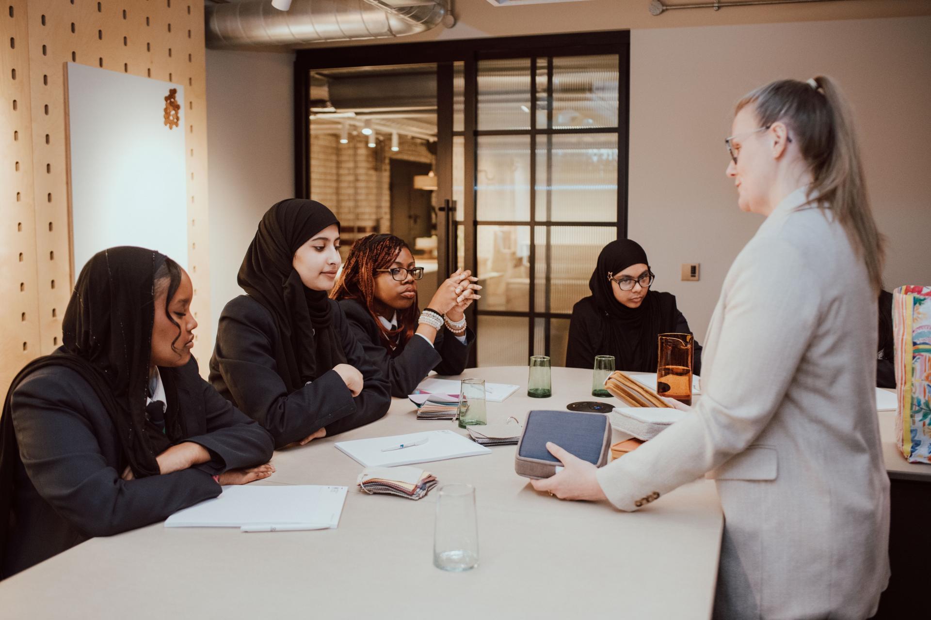 Students engage in a creative design workshop with a mentor, collaborating on interior design concepts and ideas.