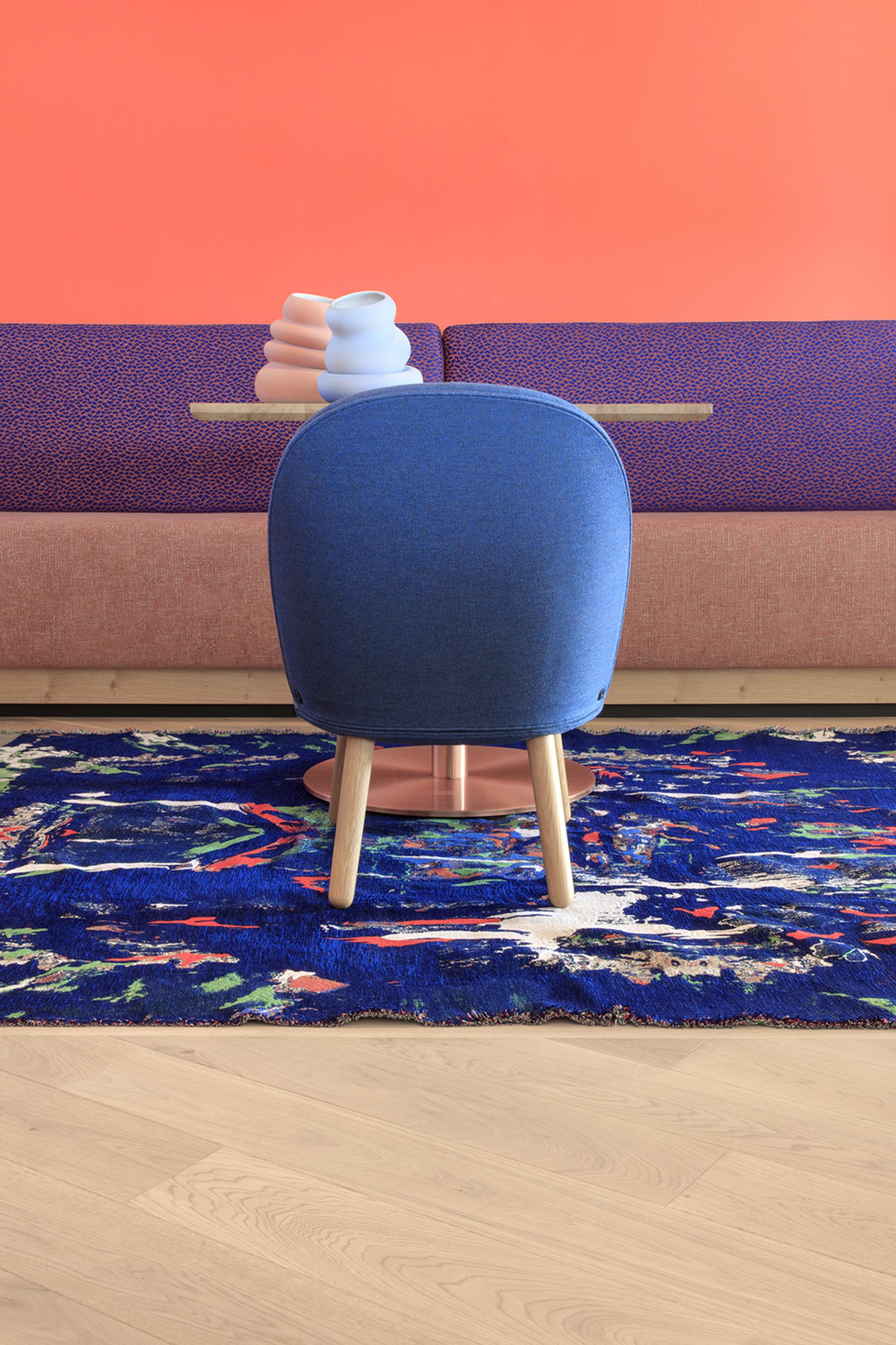 Vibrant interior of Icaro Hotel featuring a blue chair, colorful rug, and modern design elements against a warm orange wall.