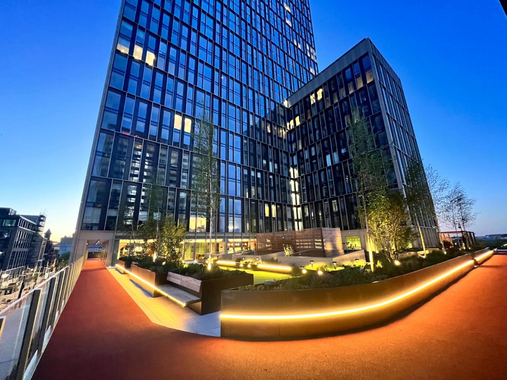 Modern residential building with illuminated garden and walkway, reflecting trends in the rental market and urban development.