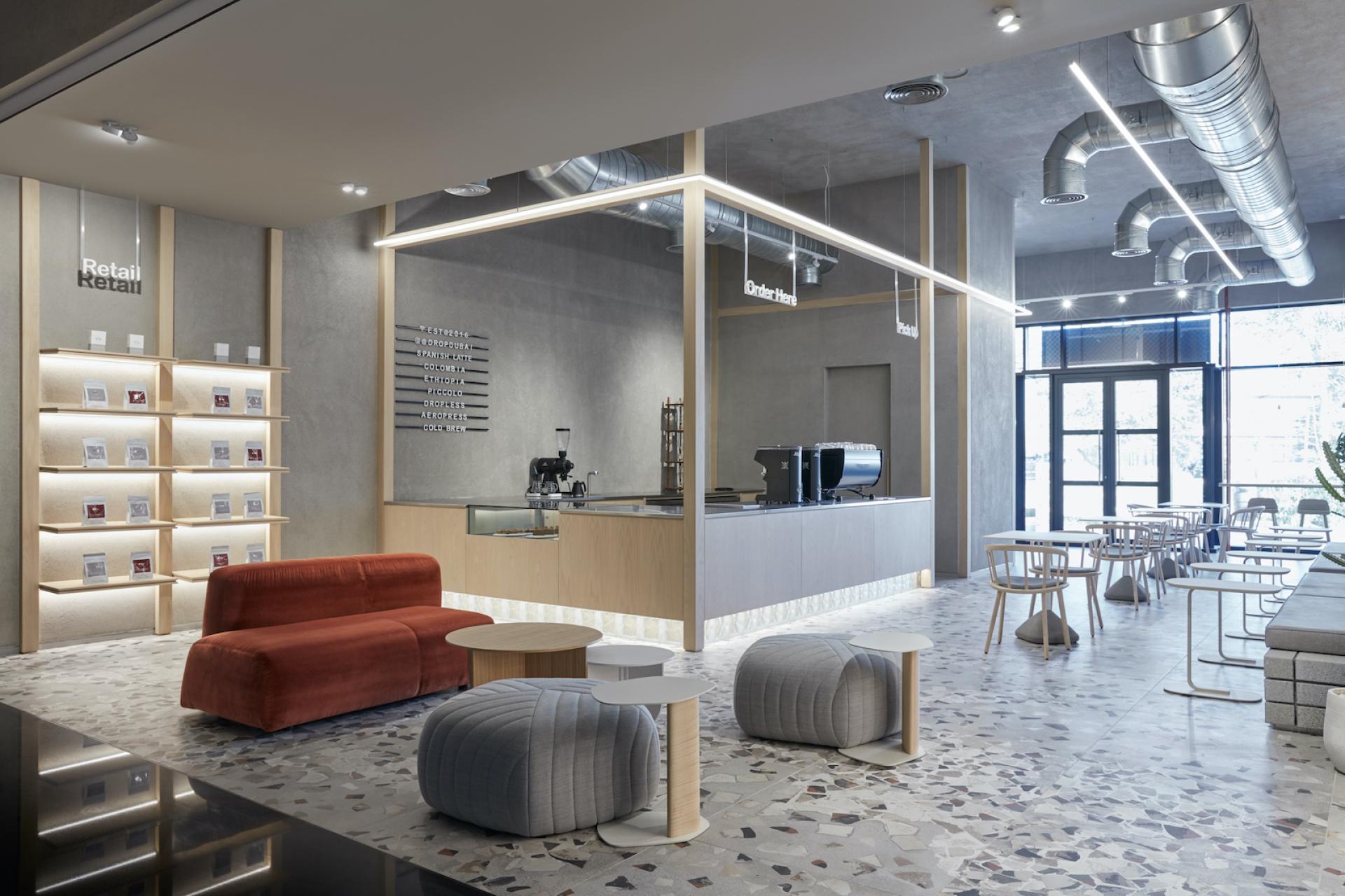 Contemporary Dubai coffee shop interior featuring minimalist furniture, textured flooring, and a stylish barista area by Roar Studio.