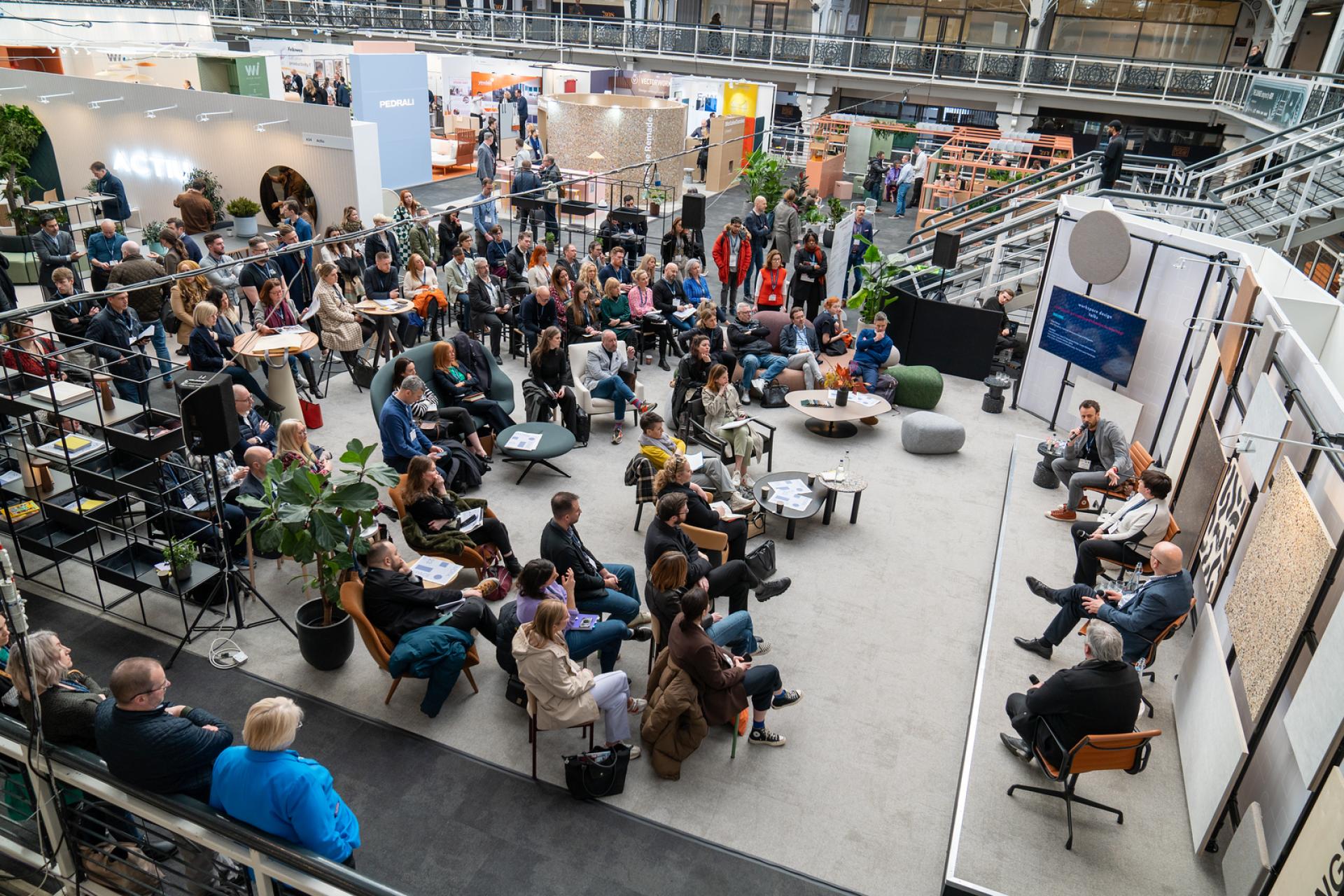 Attendees engaged in a panel discussion at the Workspace Design Show in Amsterdam, showcasing innovative workspace solutions and design trends.
