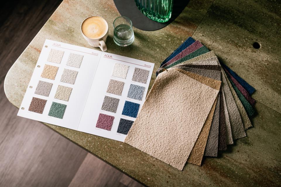 Colorful swatches of Agua Fabrics' Eden and Bouclé upholstery collections displayed on a stylish tabletop.