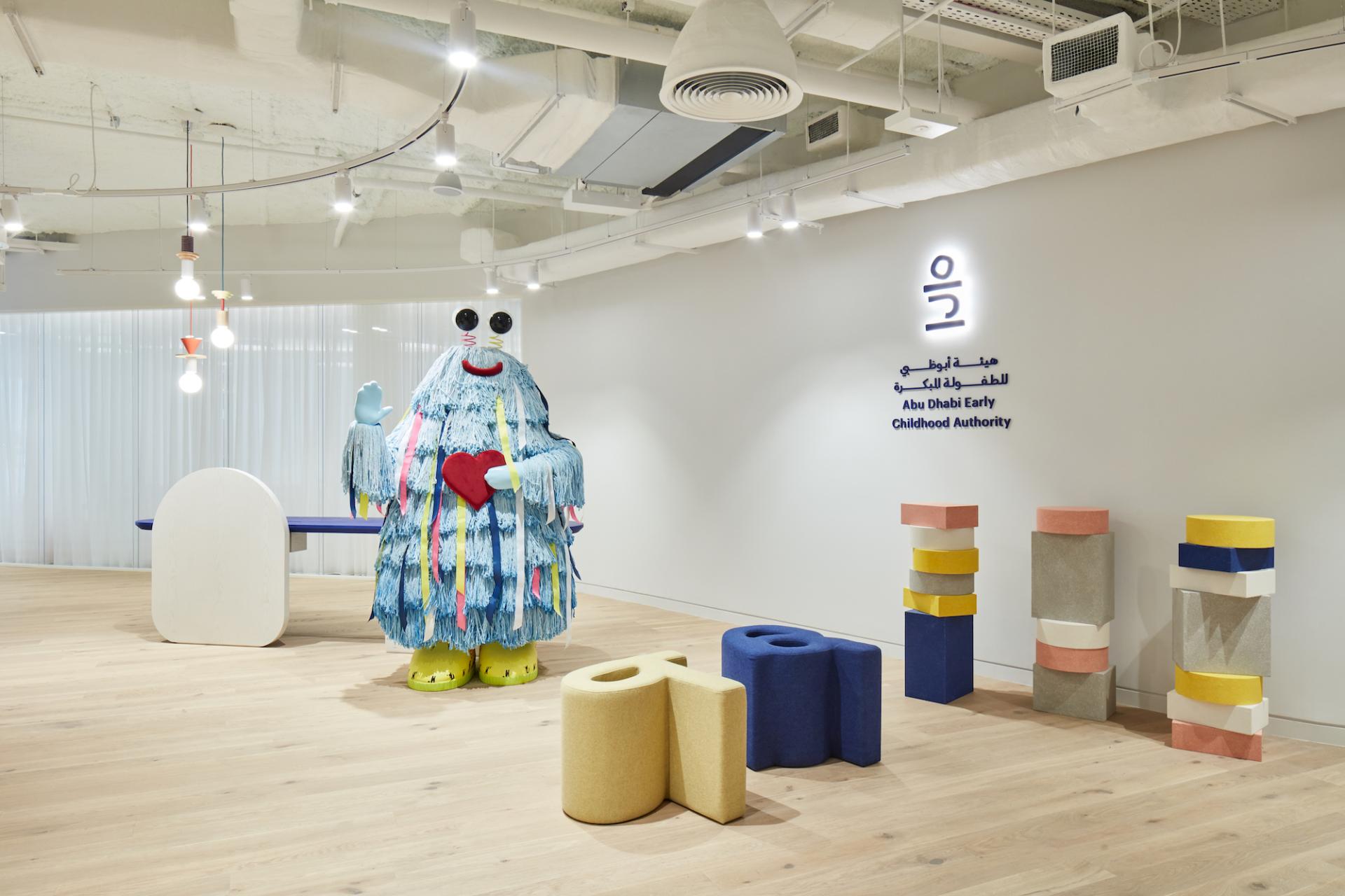 Playful interior design at Abu Dhabi's Early Childhood Authority HQ featuring colorful furniture and a whimsical character.