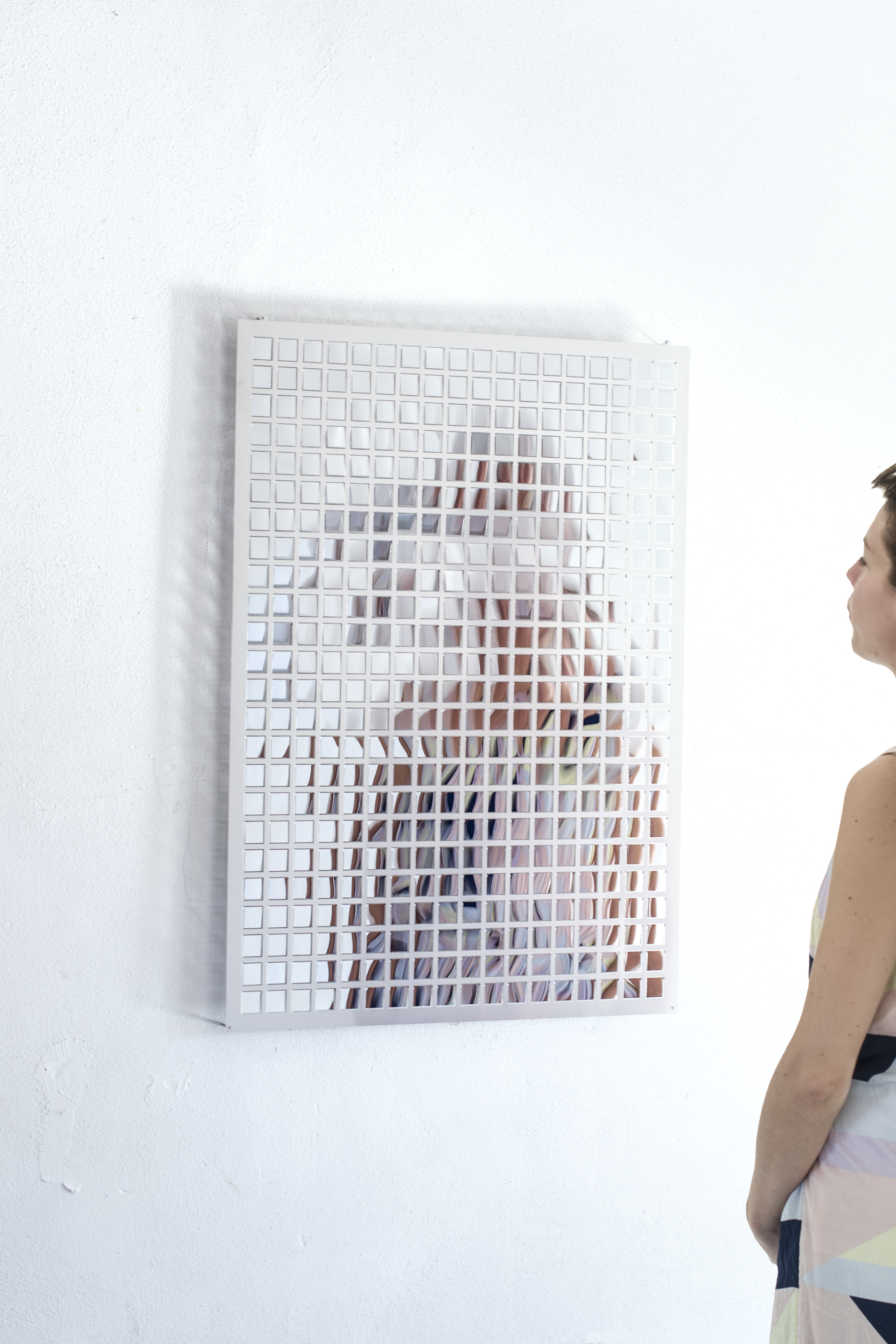 A visitor gazes at a unique mirrored artwork featuring a grid pattern, promoting sensory engagement and wellbeing.
