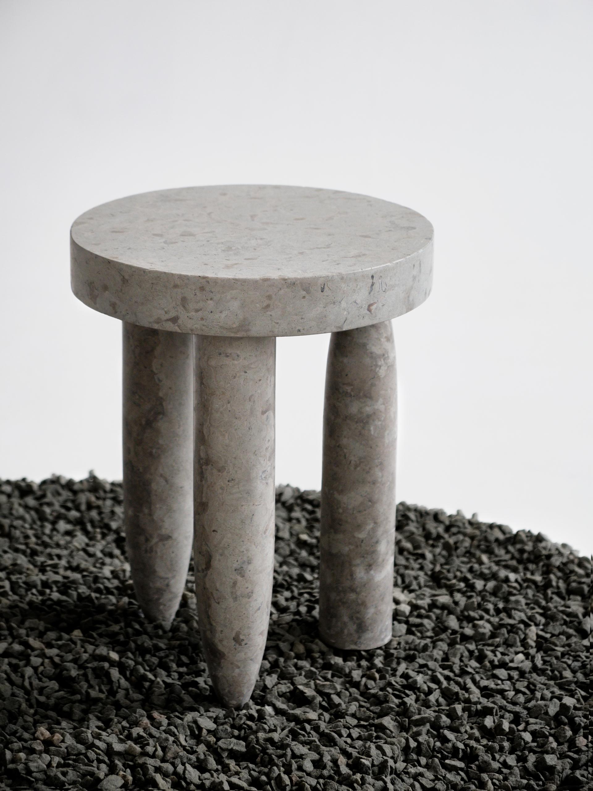 Minimalist gray stone stool displayed on textured gravel, highlighting innovative Baltic design and craftsmanship.
