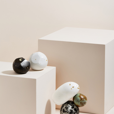 Sculptures by Vic Wright featuring uniquely shaped decorative orbs displayed on minimalist pedestals against a soft background.