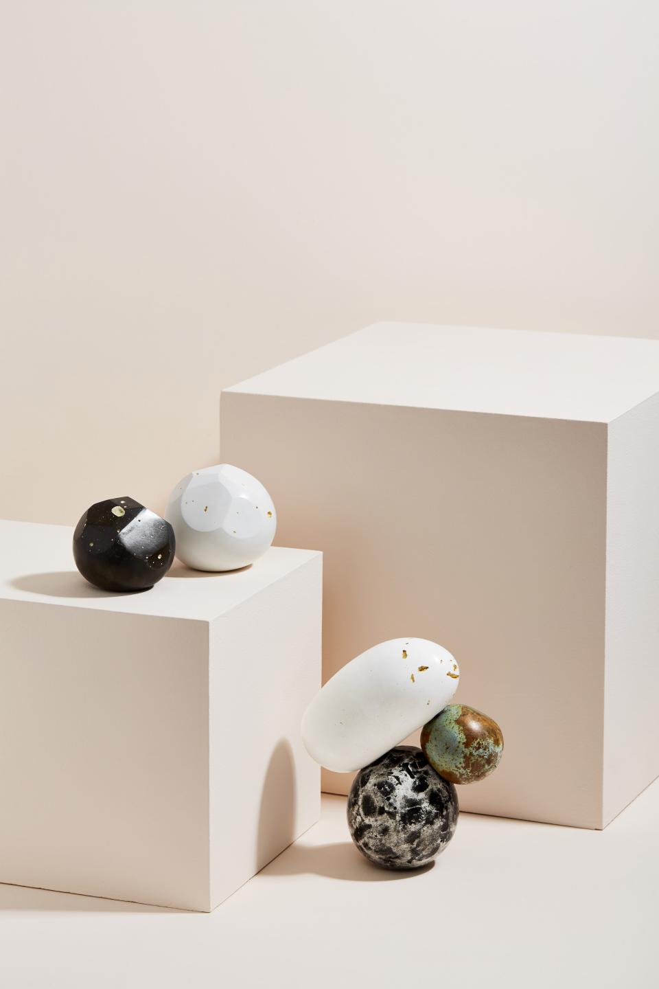 Sculptures by Vic Wright featuring uniquely shaped decorative orbs displayed on minimalist pedestals against a soft background.