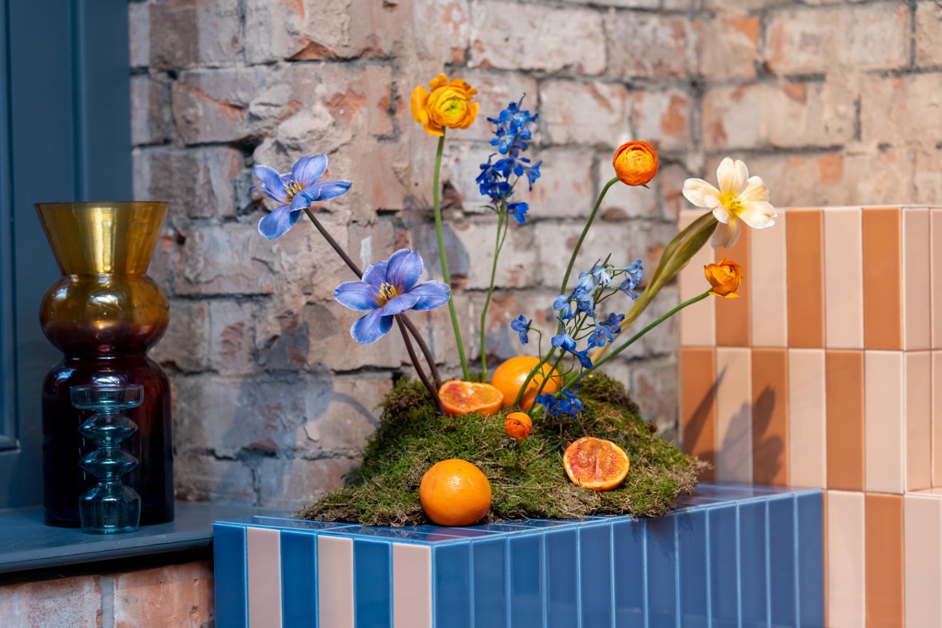 Colorful flowers and fruit arranged on moss, highlighting playful design with tile combinations in the Färgblock collection.