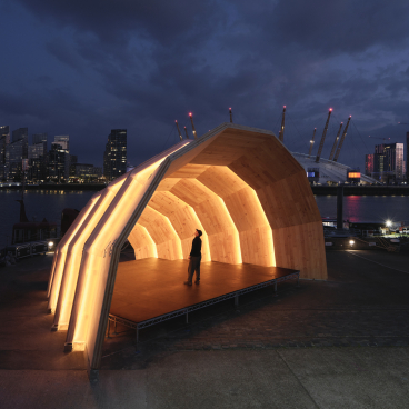 Eucalyptus CLT pavilion named The Armadillo illuminated at night, showcasing innovative design along the Thames waterfront.