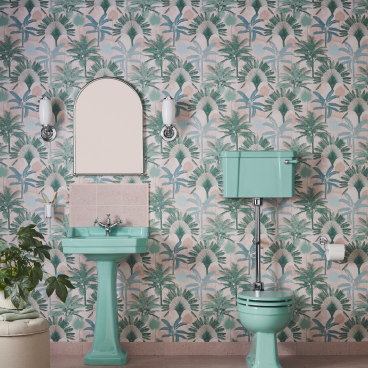 Stylish bathroom featuring Enchanted Blue ceramic sink and toilet against a palm-patterned wallpaper backdrop.