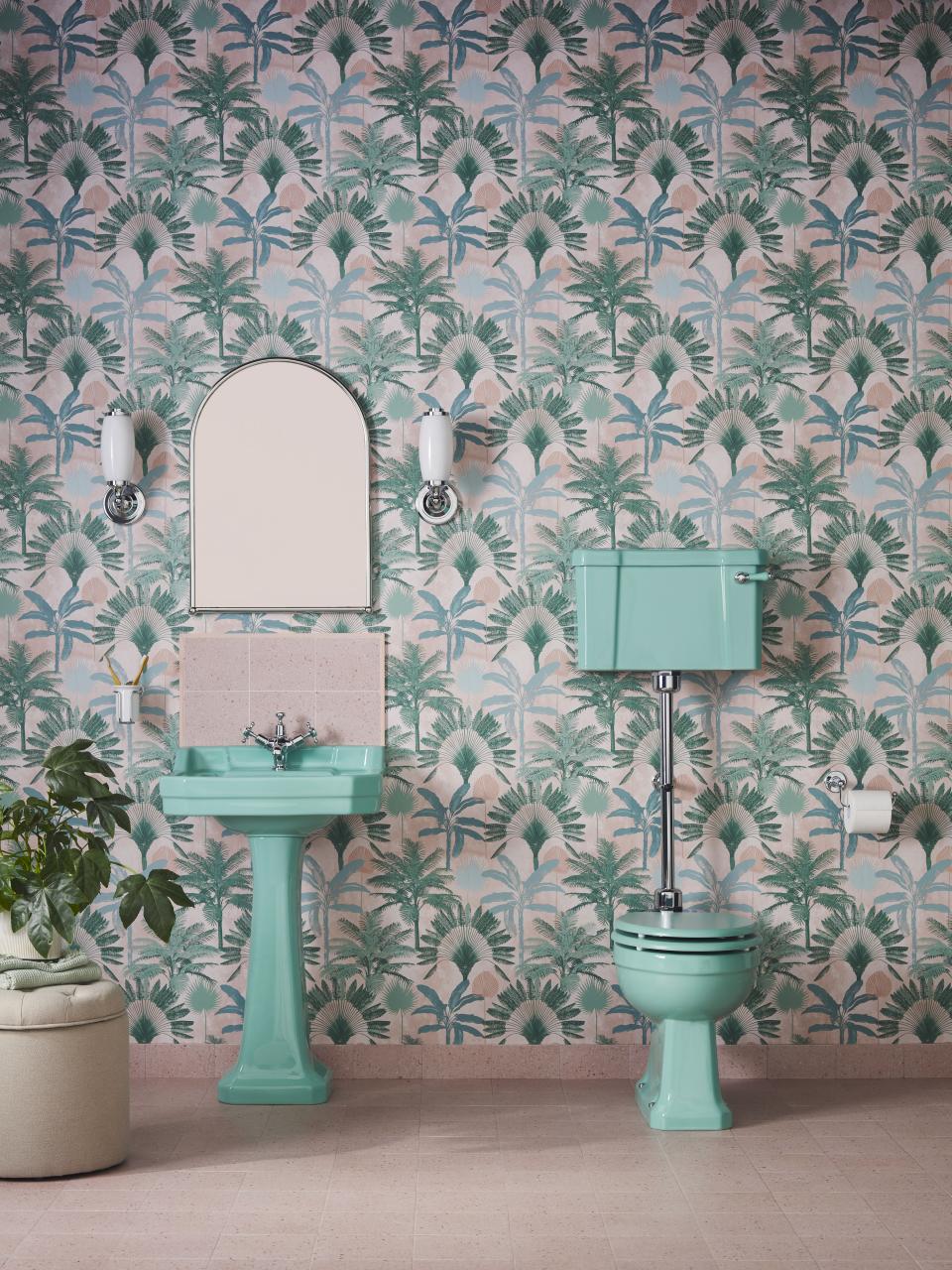 Stylish bathroom featuring Enchanted Blue ceramic sink and toilet against a palm-patterned wallpaper backdrop.