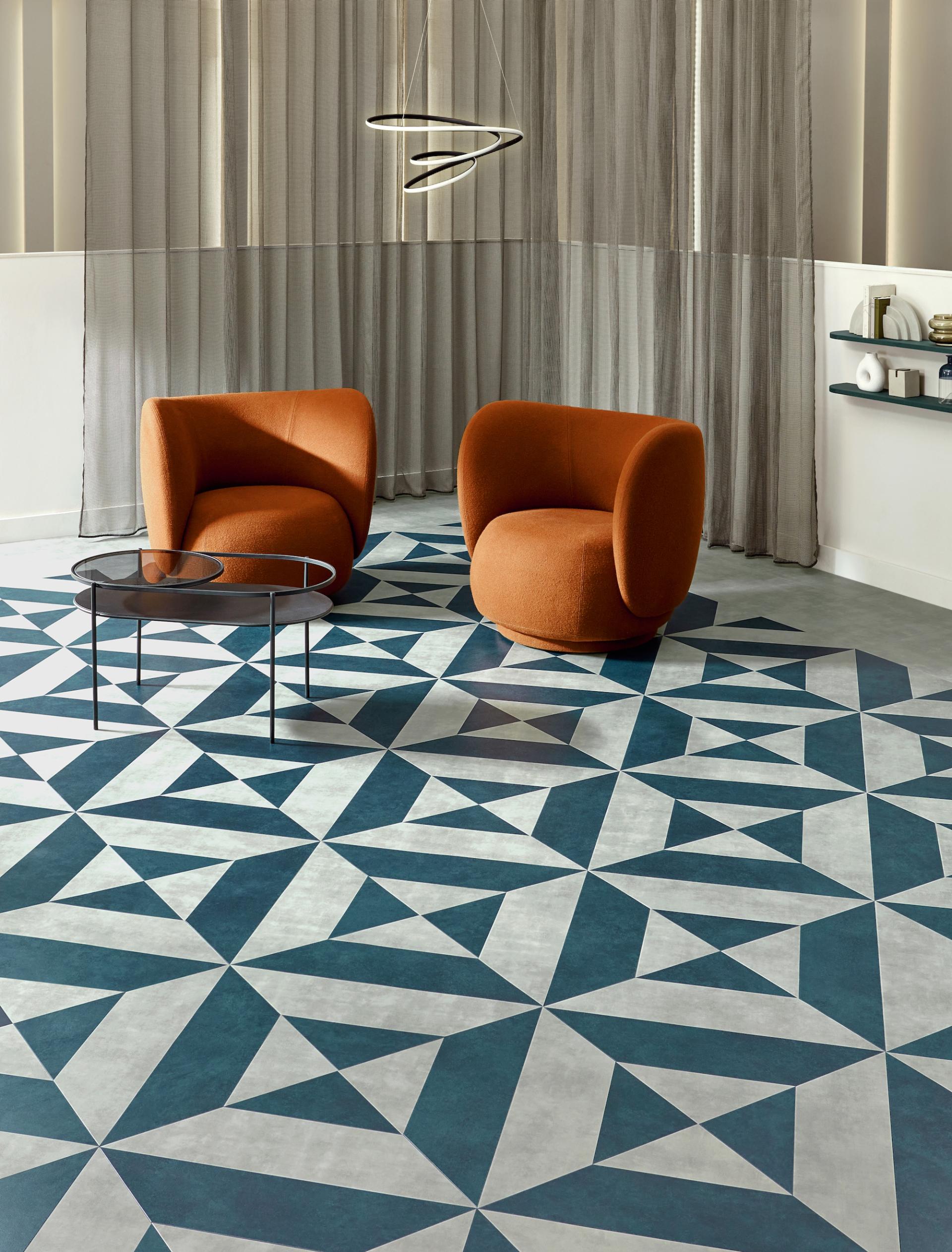 Geometric patterned flooring in shades of blue and gray, accented by modern orange seating and elegant decor.